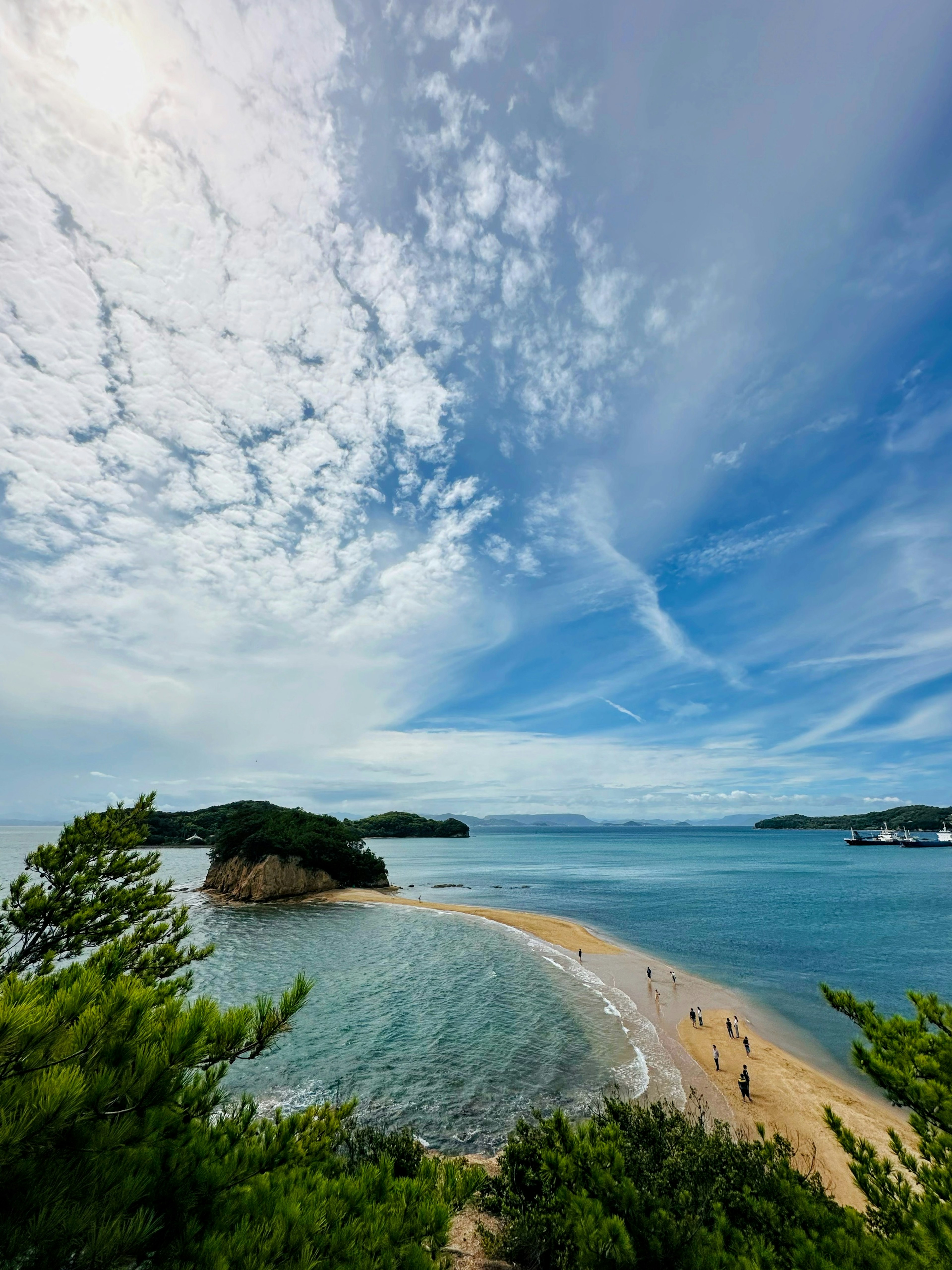 Beautiful beach scene under a blue sky with people walking