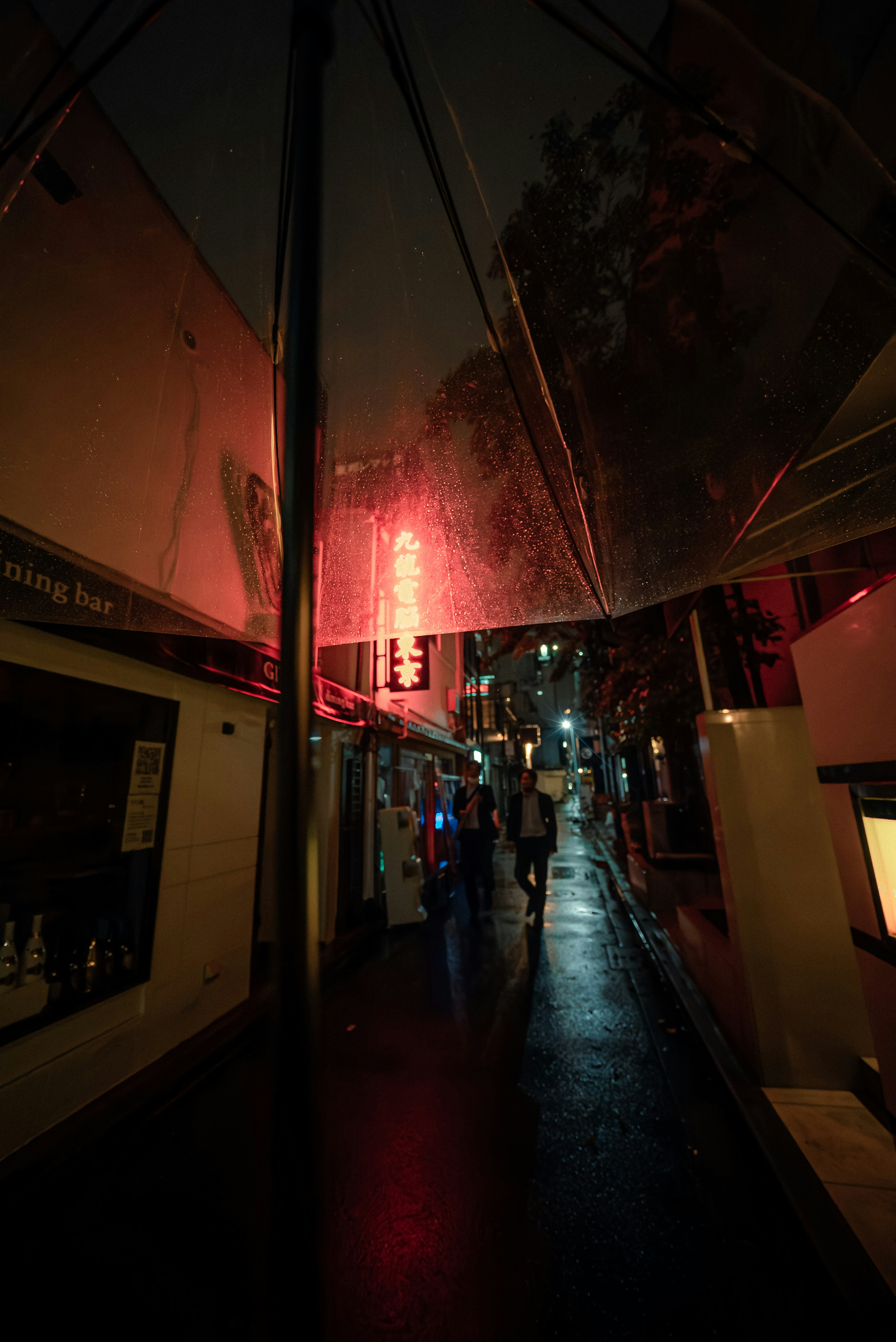 Una notte piovosa in una strada poco illuminata con un'insegna al neon rossa