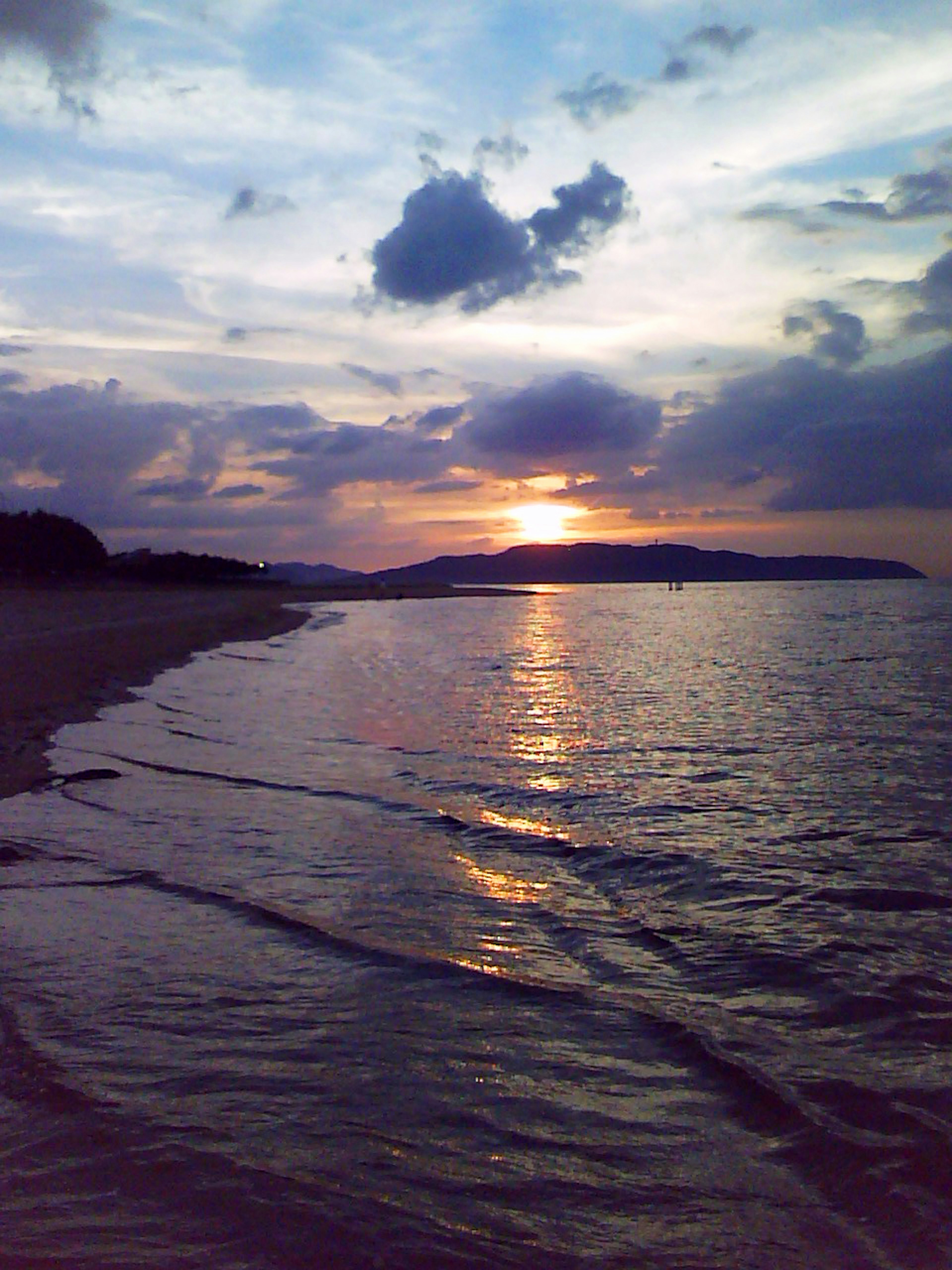 Hermoso paisaje marítimo con costa y reflejos del atardecer