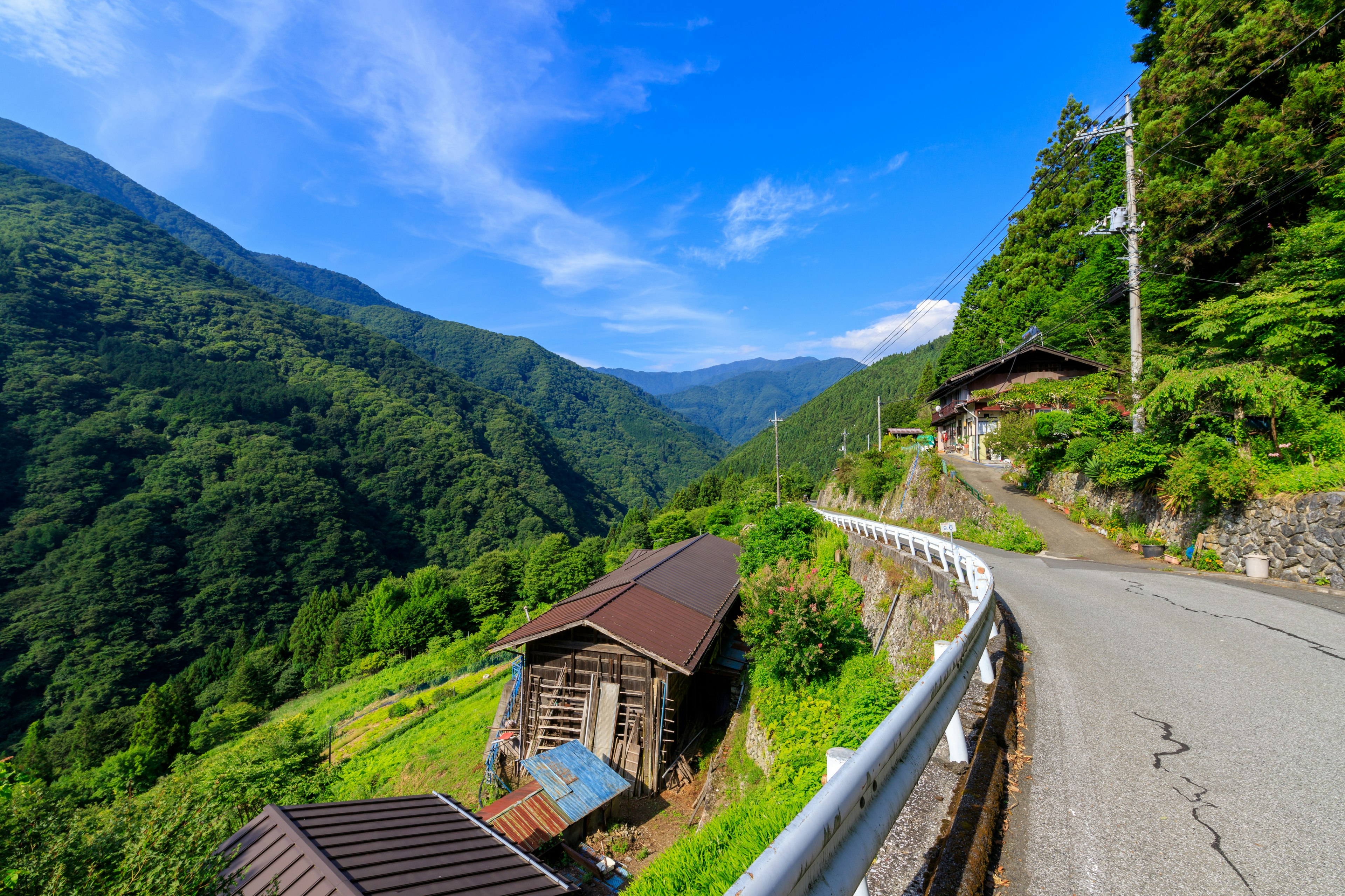 Curved road surrounded by lush mountains and old houses