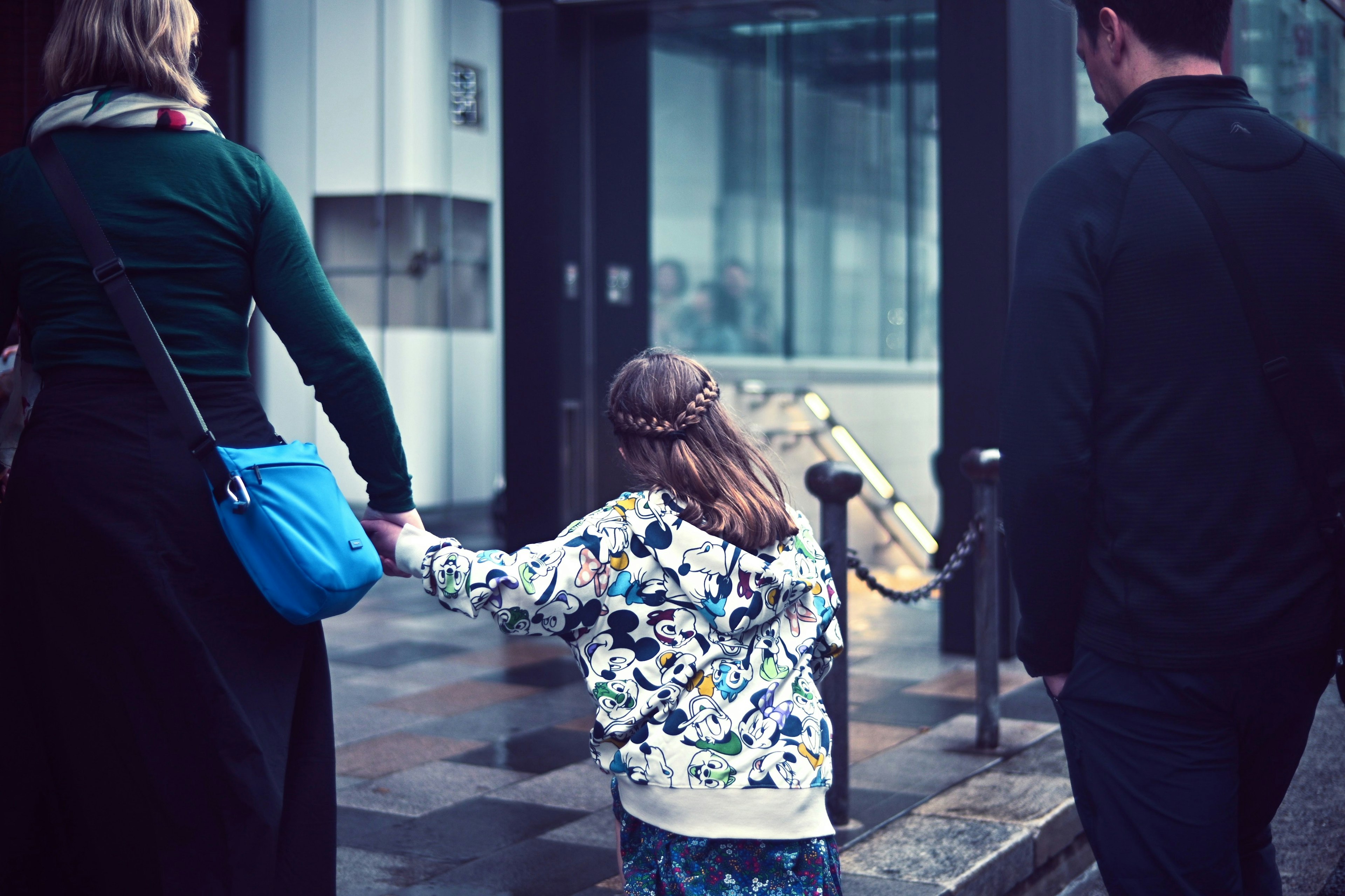 Back view of a child holding hands with adults while walking