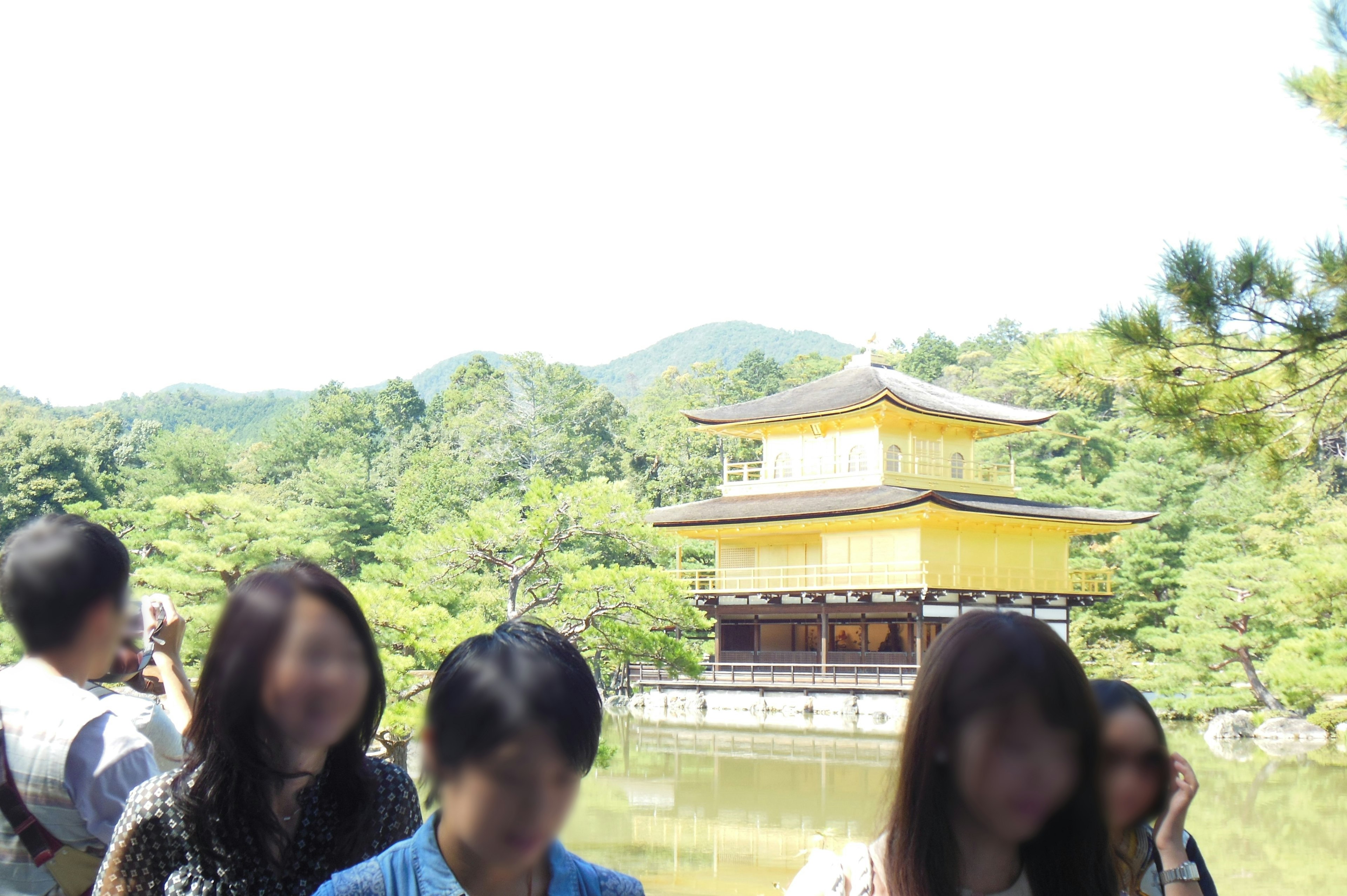 Personas reunidas frente al Kinkaku-ji con vegetación exuberante