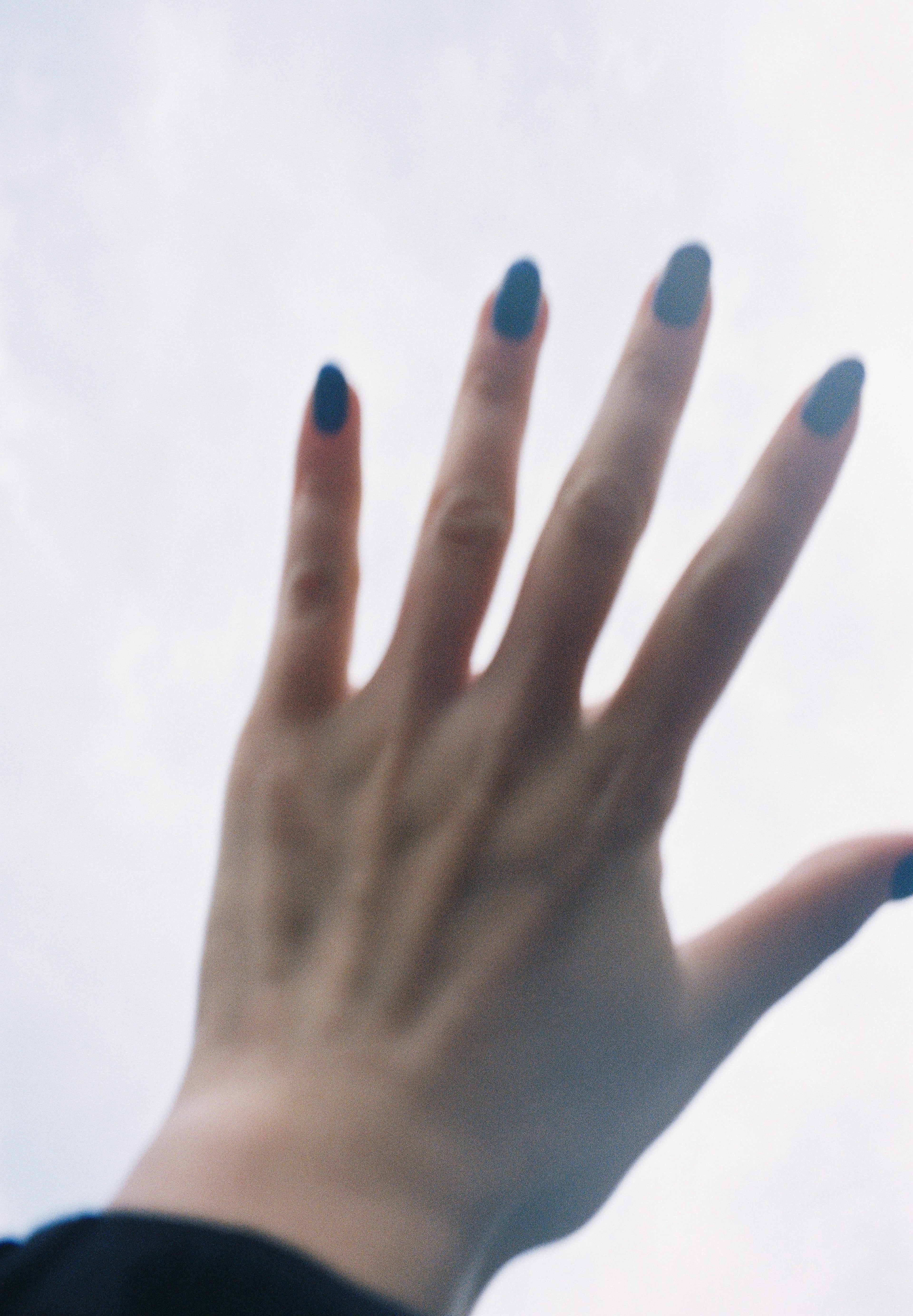 A hand reaching towards the sky with manicured nails