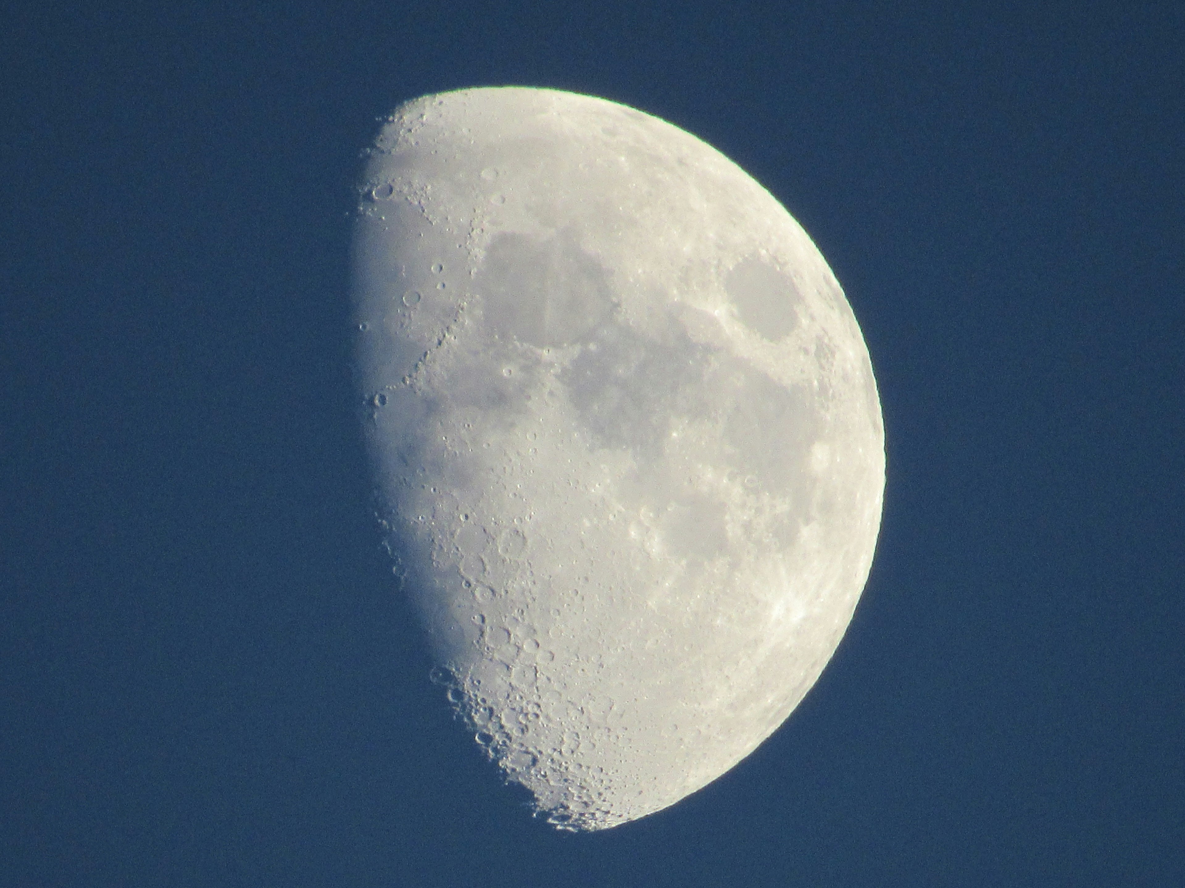 Close-up bulan setengah di langit biru