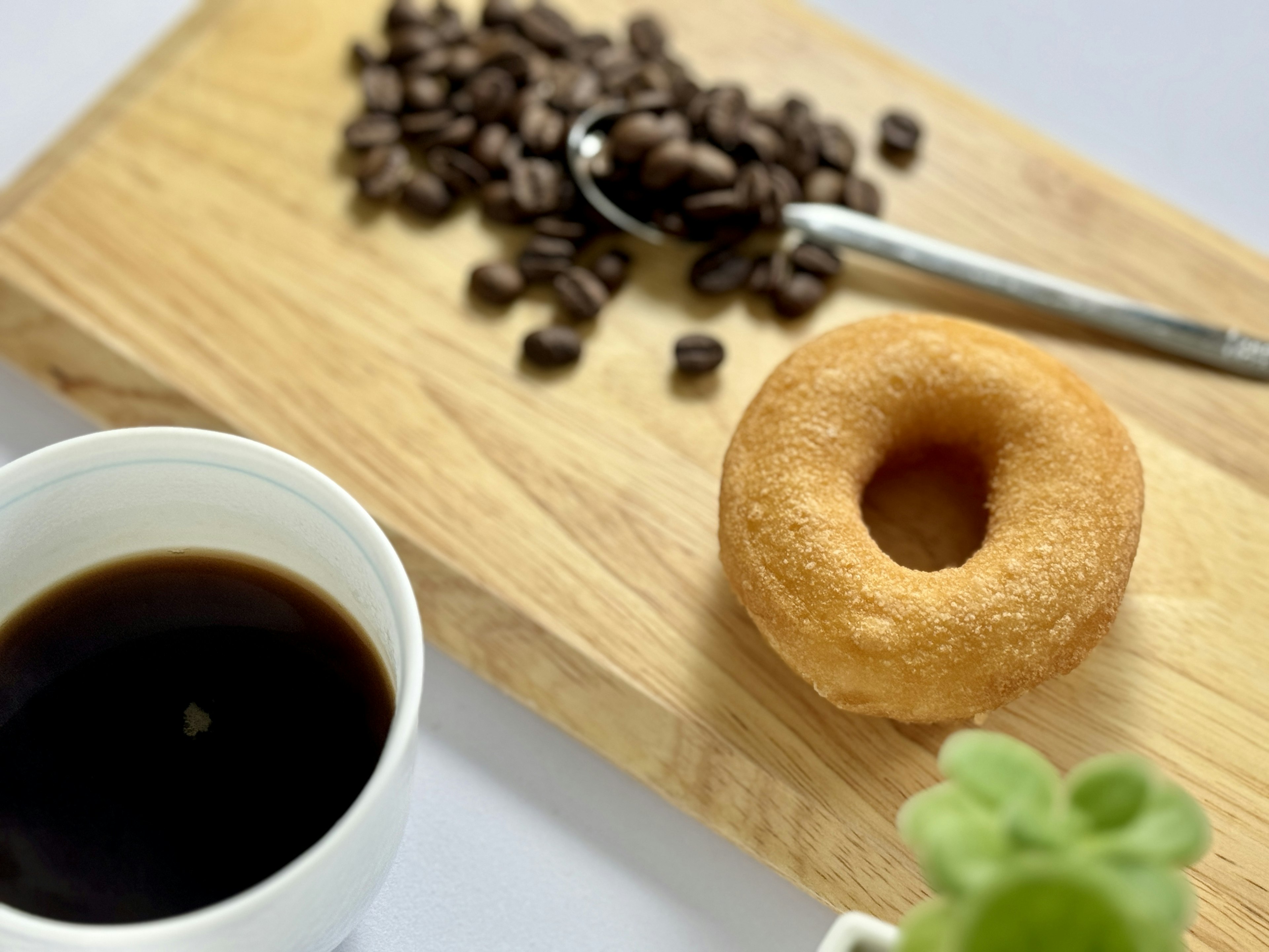 Granos de café cuchara donut café y planta en maceta sobre tabla de madera