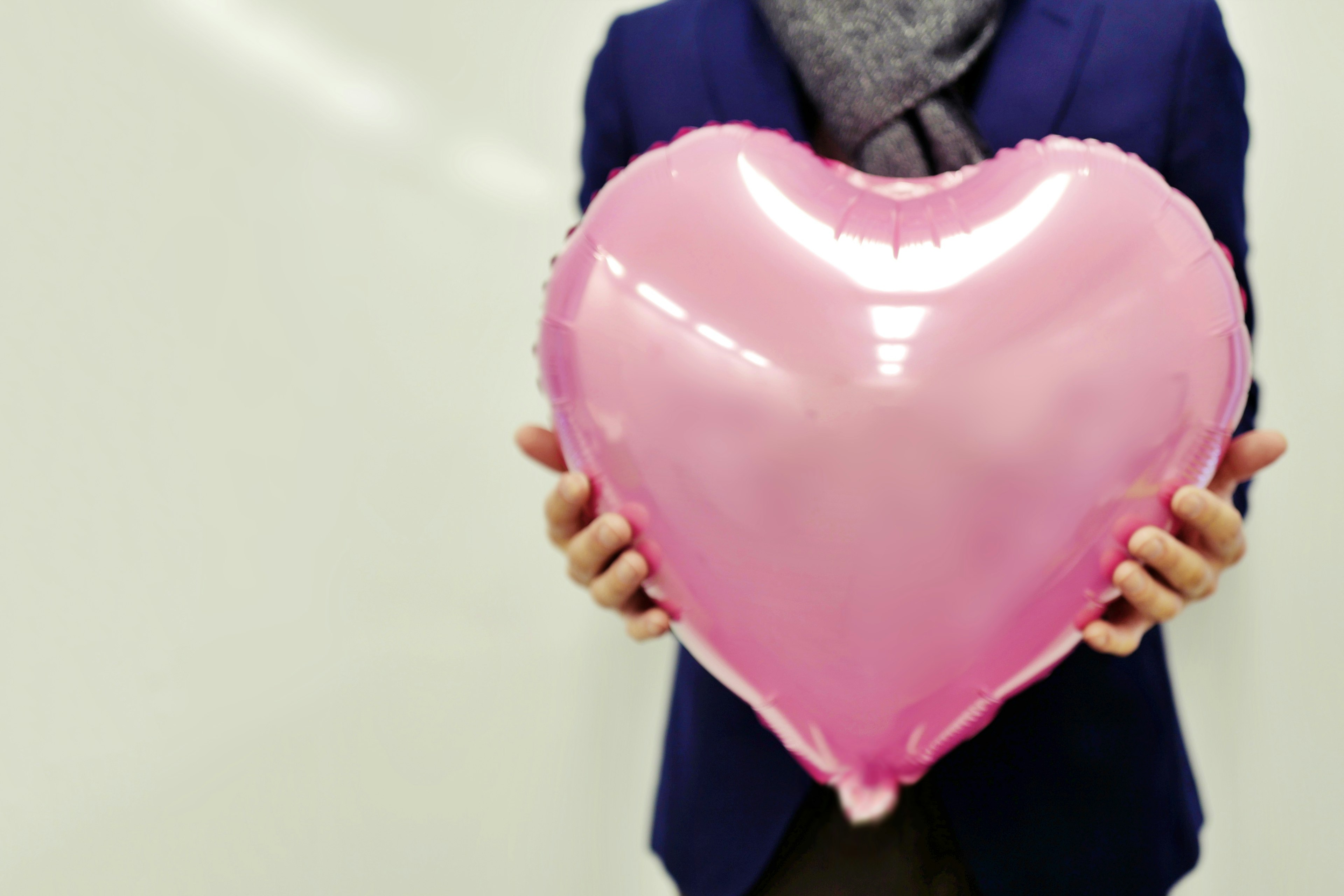 Persona sosteniendo un gran globo en forma de corazón rosa