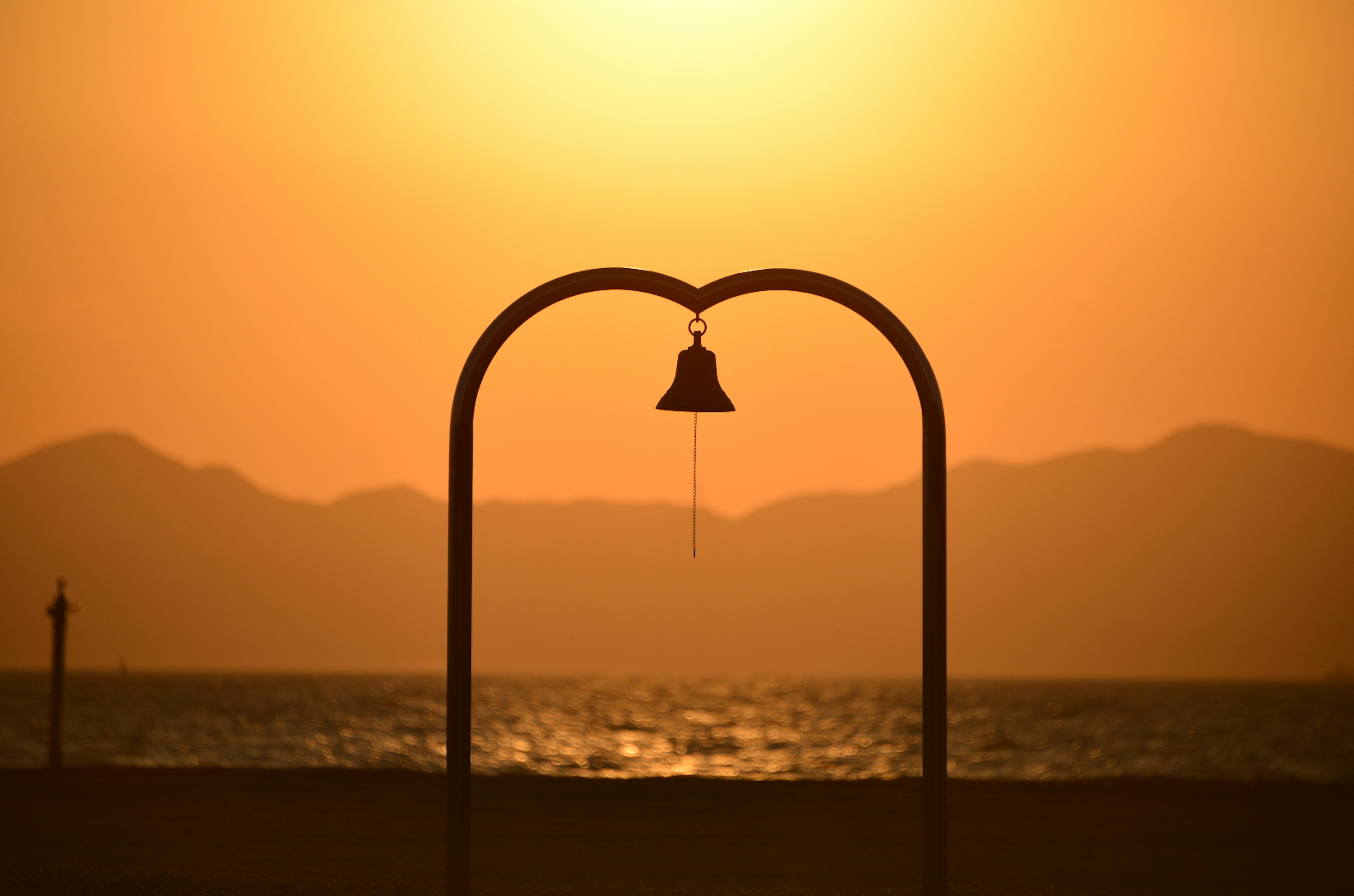 Hermoso paisaje de atardecer con un marco en forma de corazón y una campana