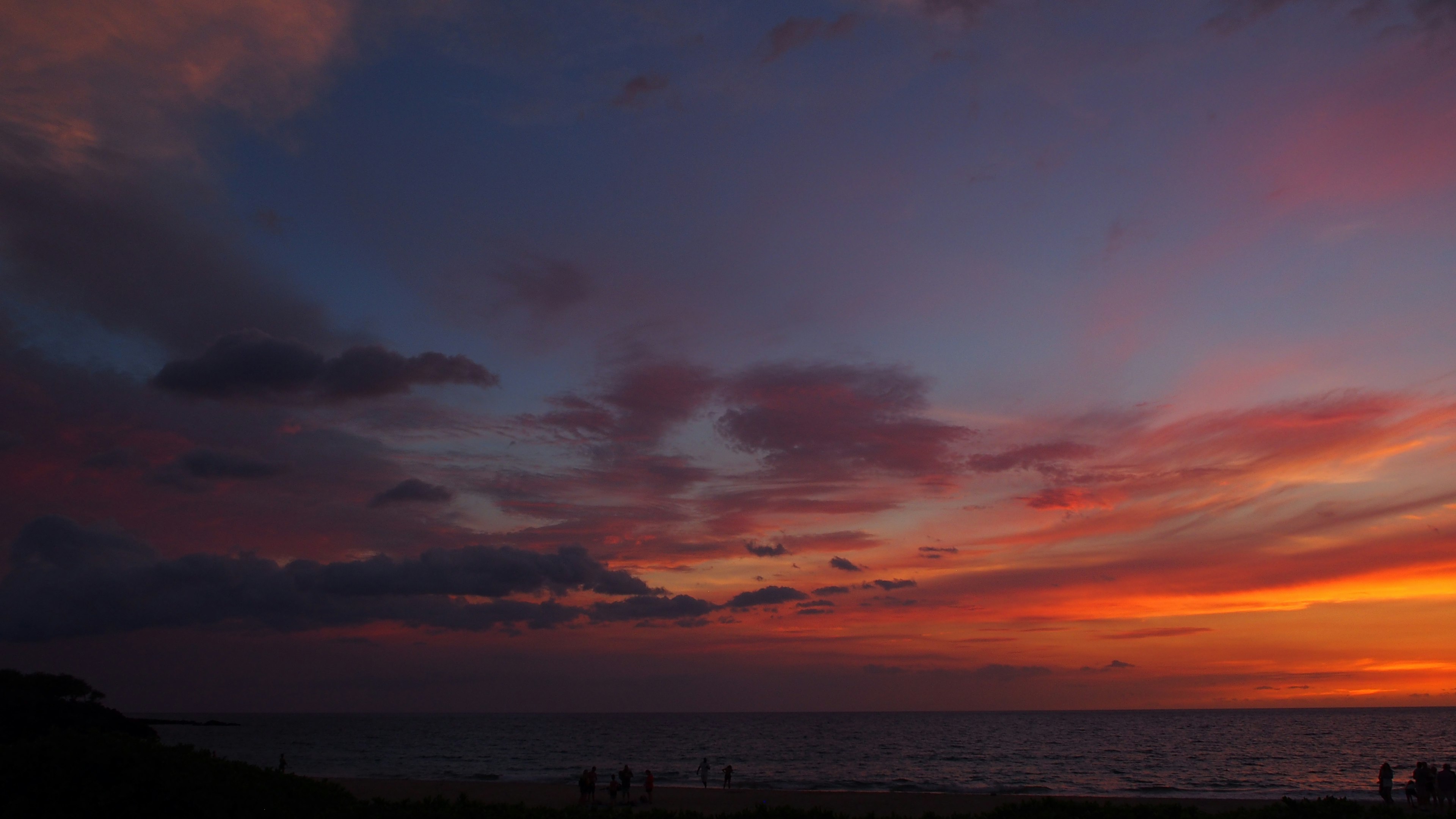 Coucher de soleil vibrant sur l'océan avec des nuages colorés et un ciel orange