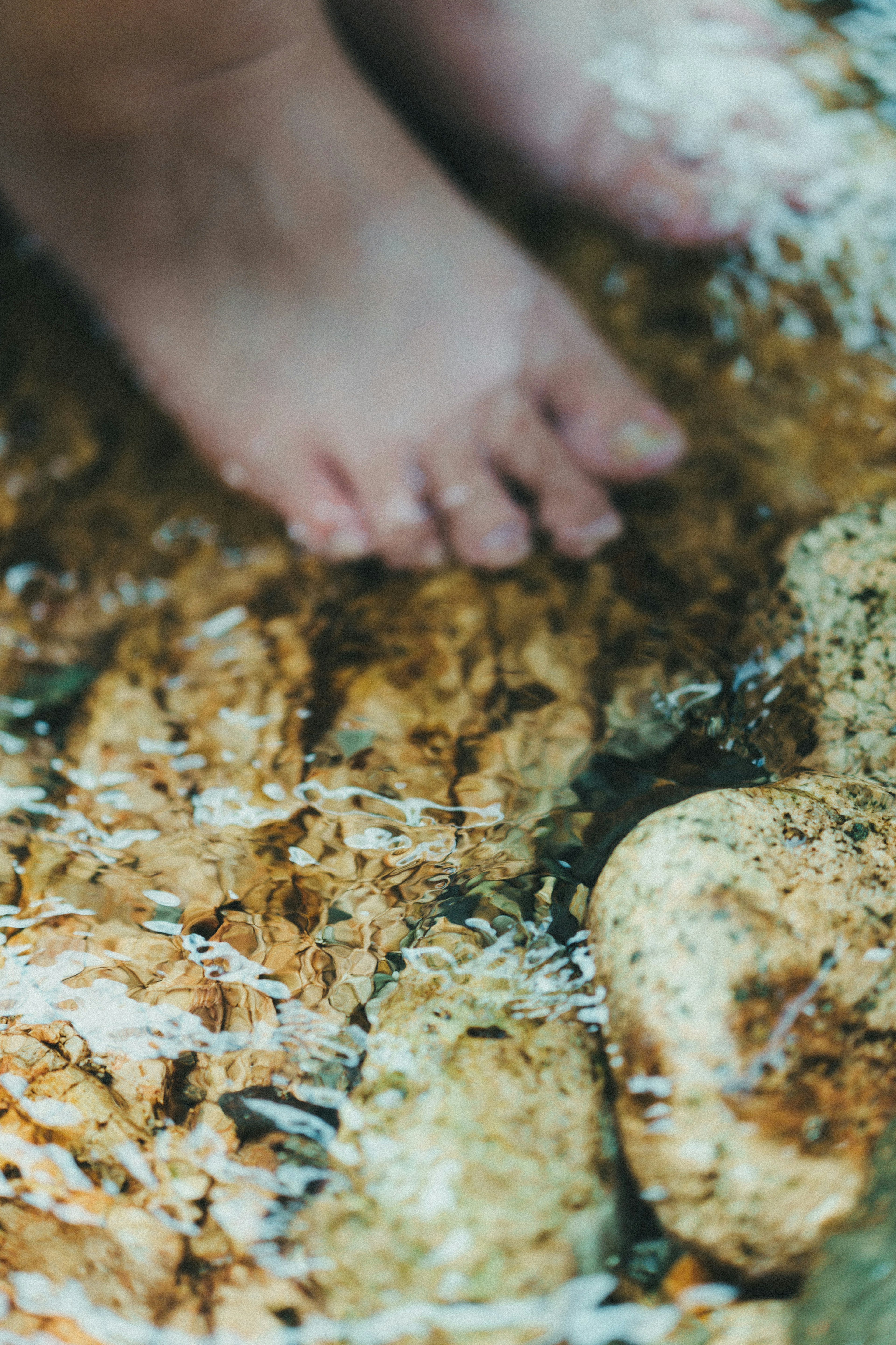 Primo piano di piedi nudi su pietre vicino all'acqua