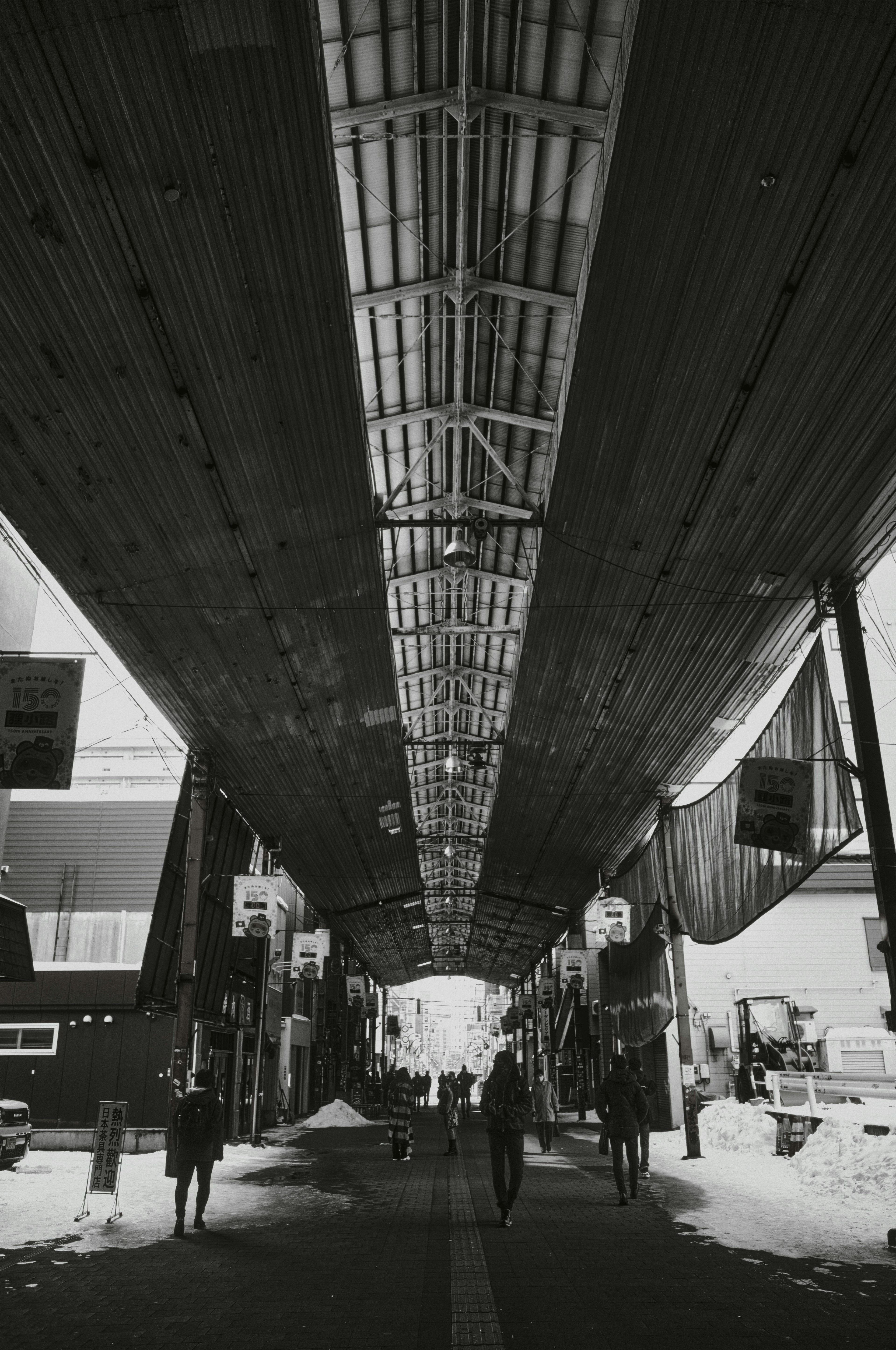 Black and white photo of people walking under an arcade