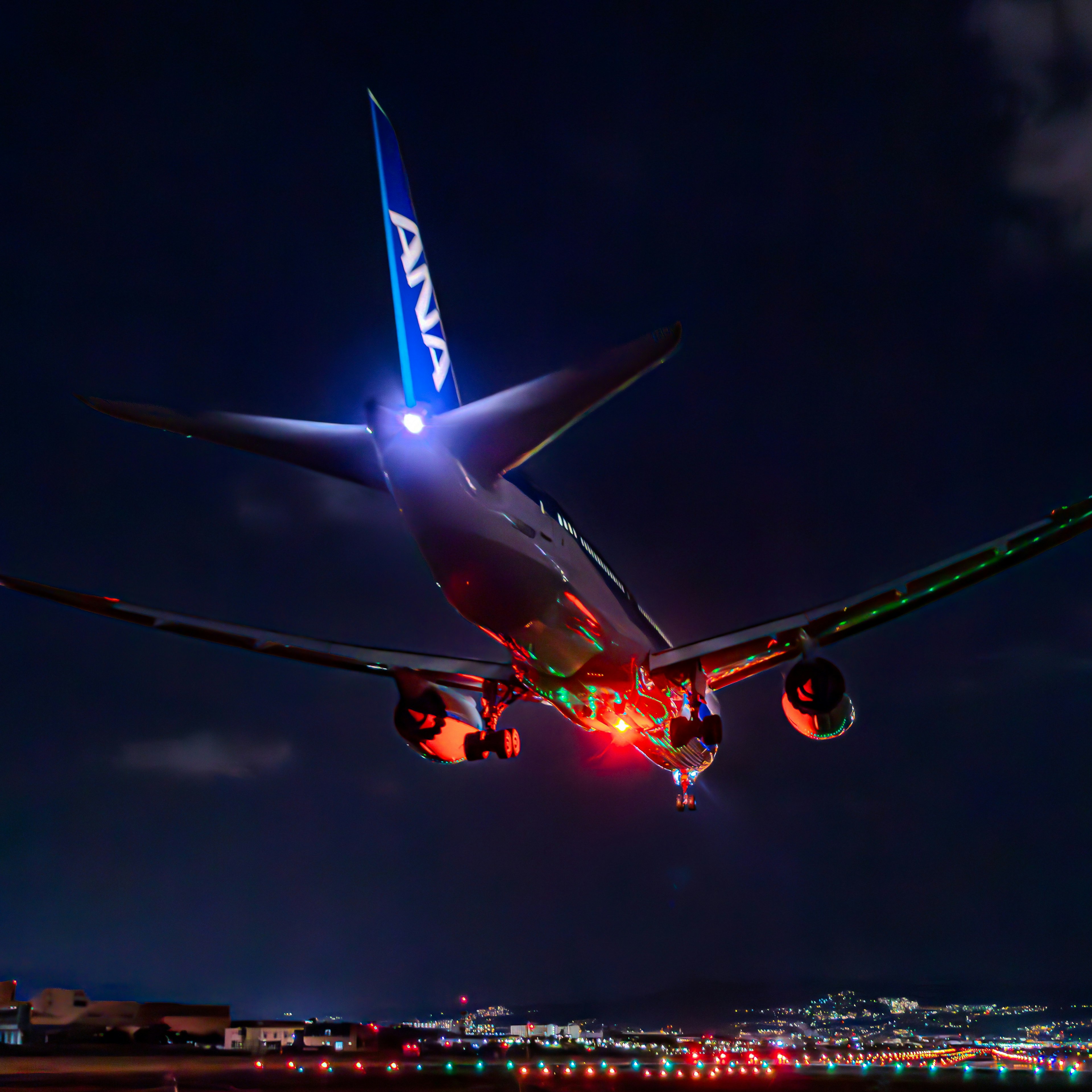 ANA airplane landing at night with vibrant lights