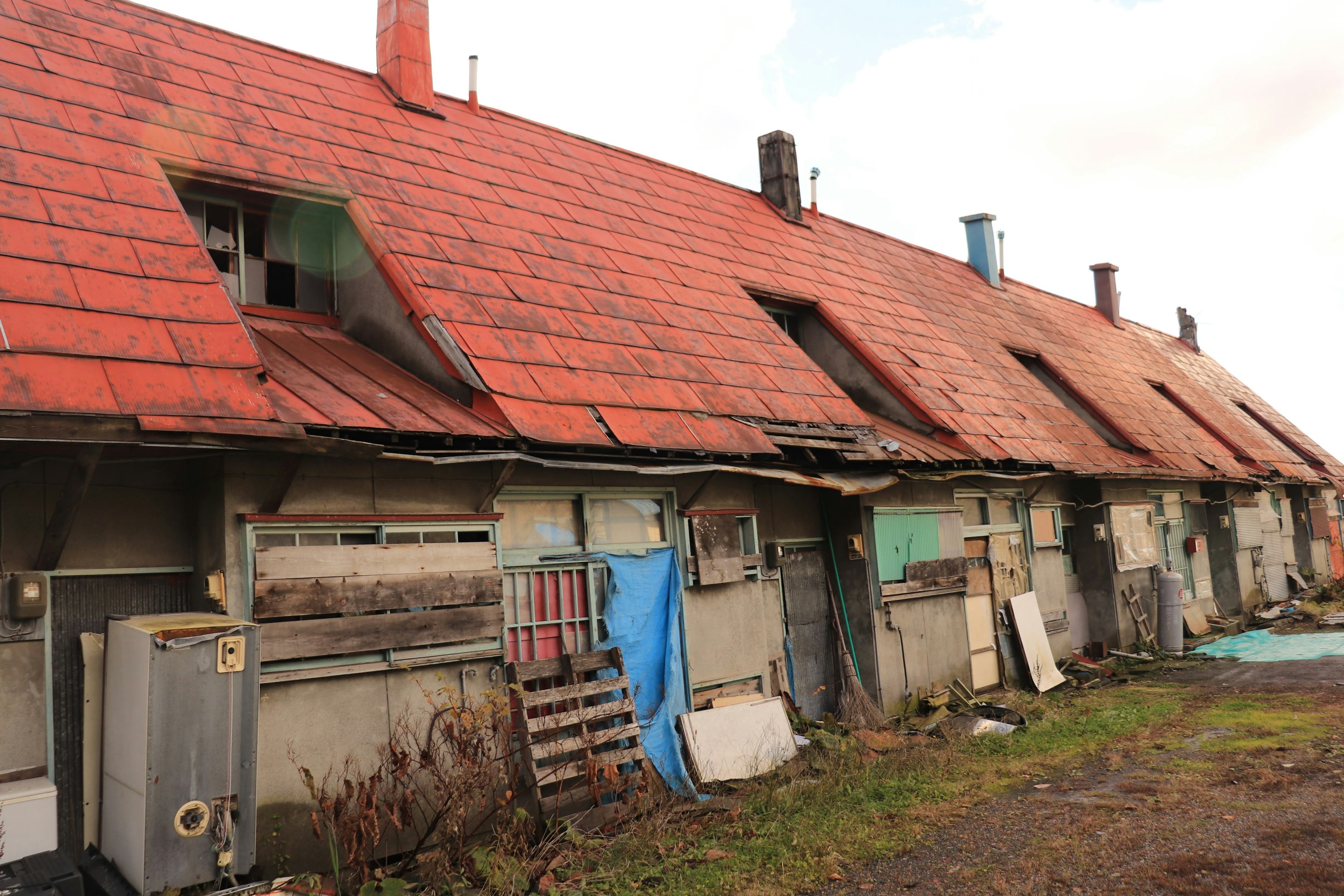 Exterior of an old building with a red roof damaged windows and walls