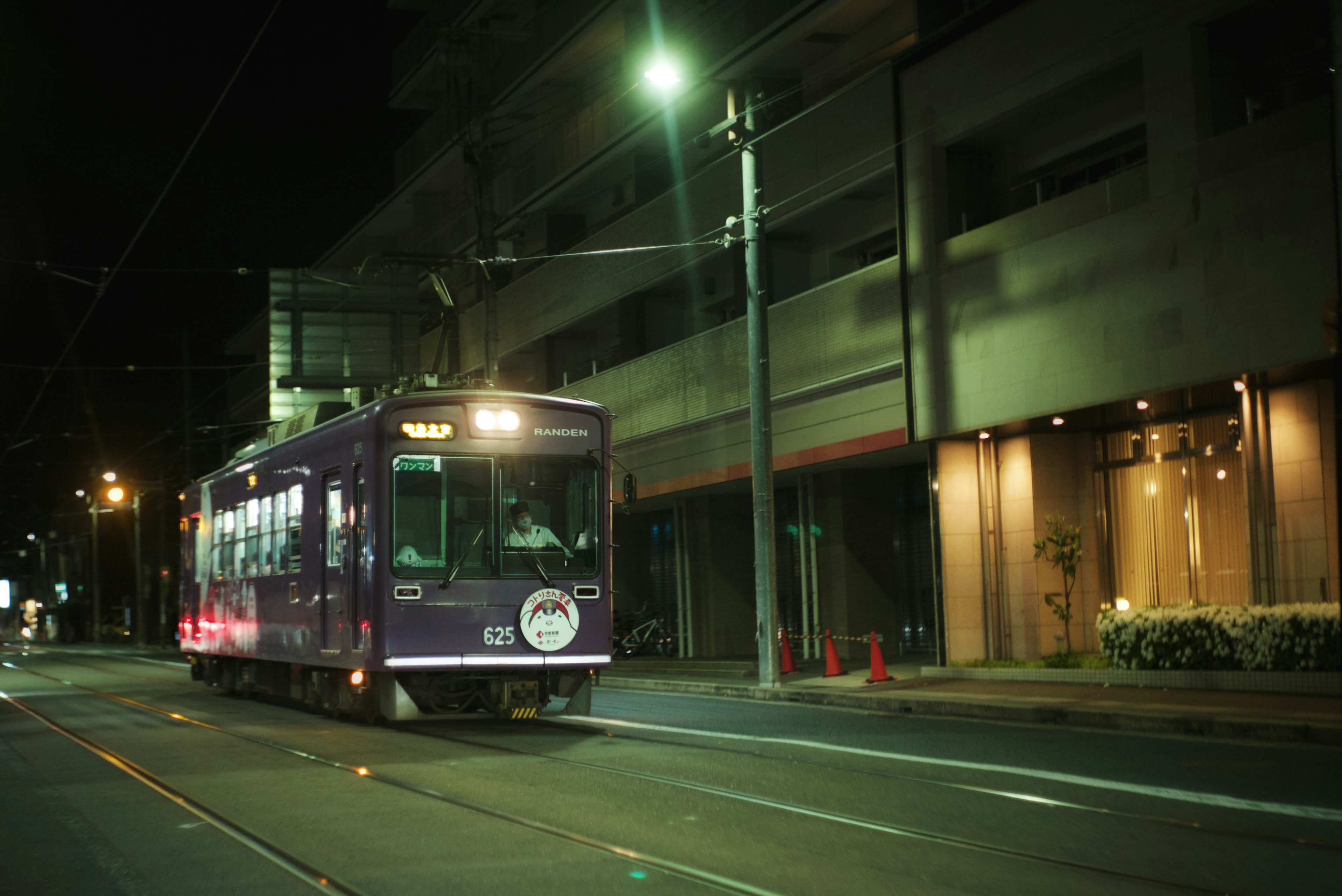 Purple tram running through the city at night with illuminated buildings