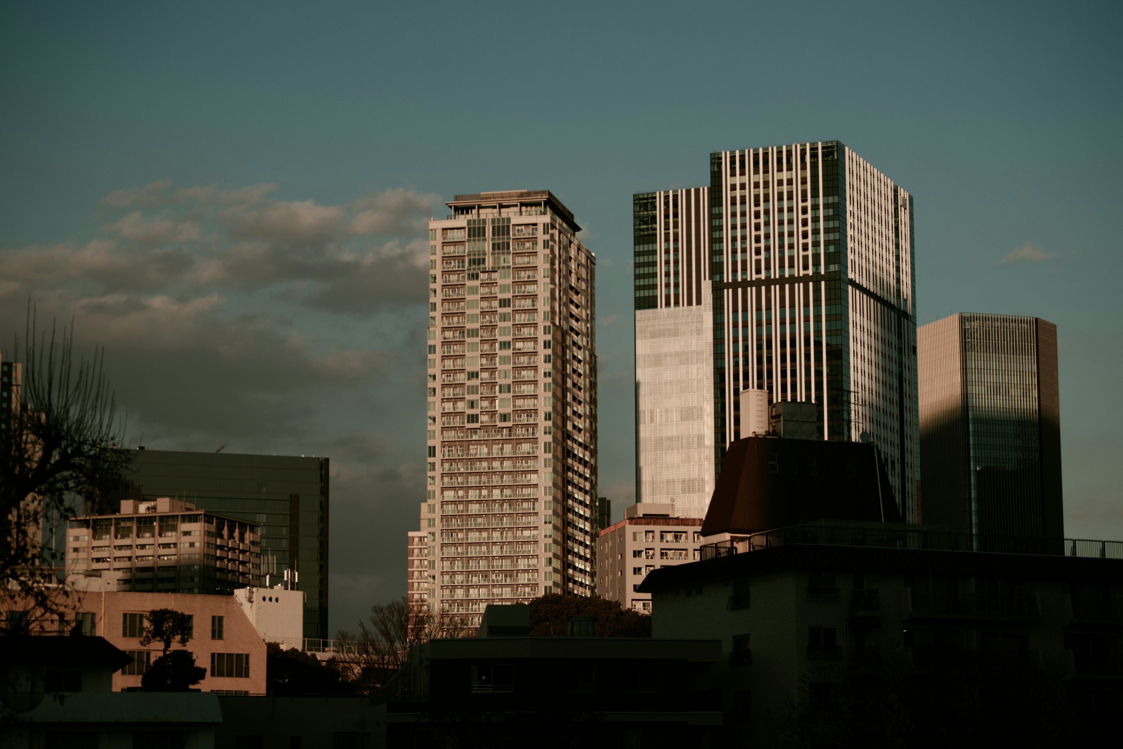 都市の高層ビル群が夕暮れの光に照らされている