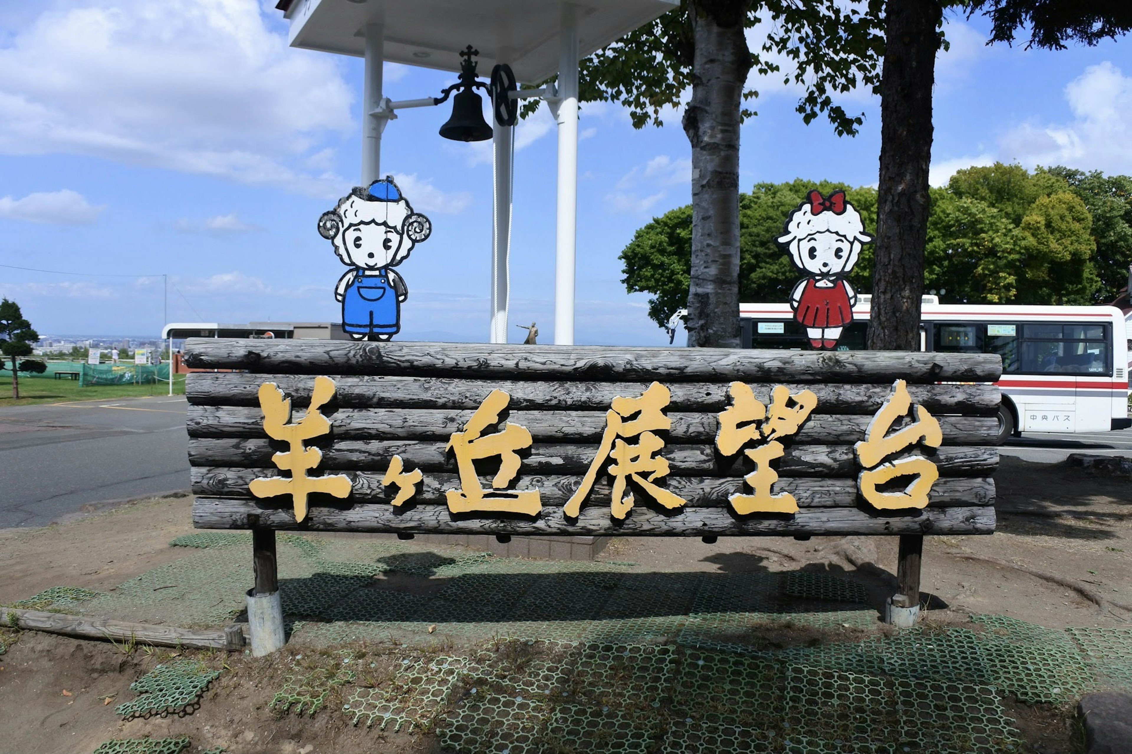 Wooden sign featuring cartoon characters at a scenic viewpoint