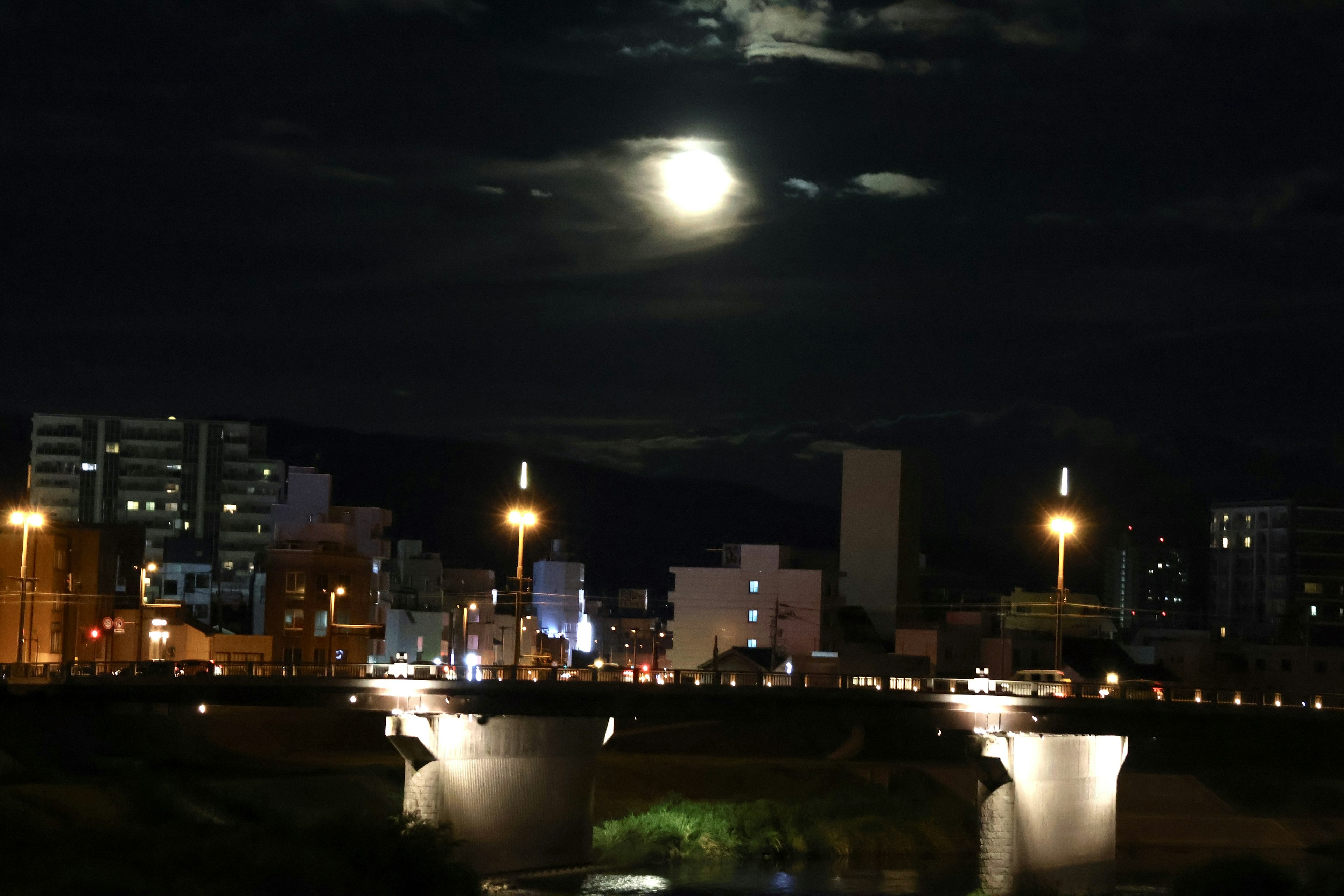 Vista notturna di un fiume e dello skyline urbano sotto una luna piena