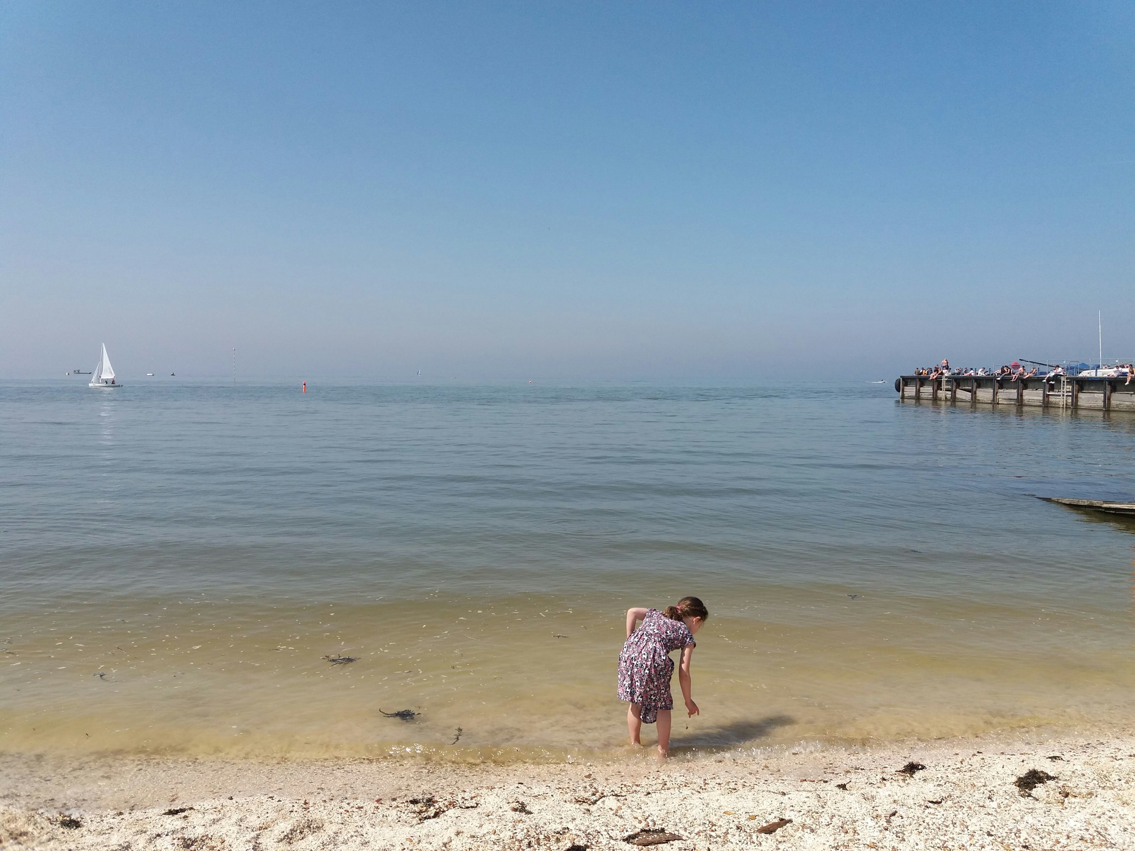 Niño jugando en una playa tranquila con mar calmado