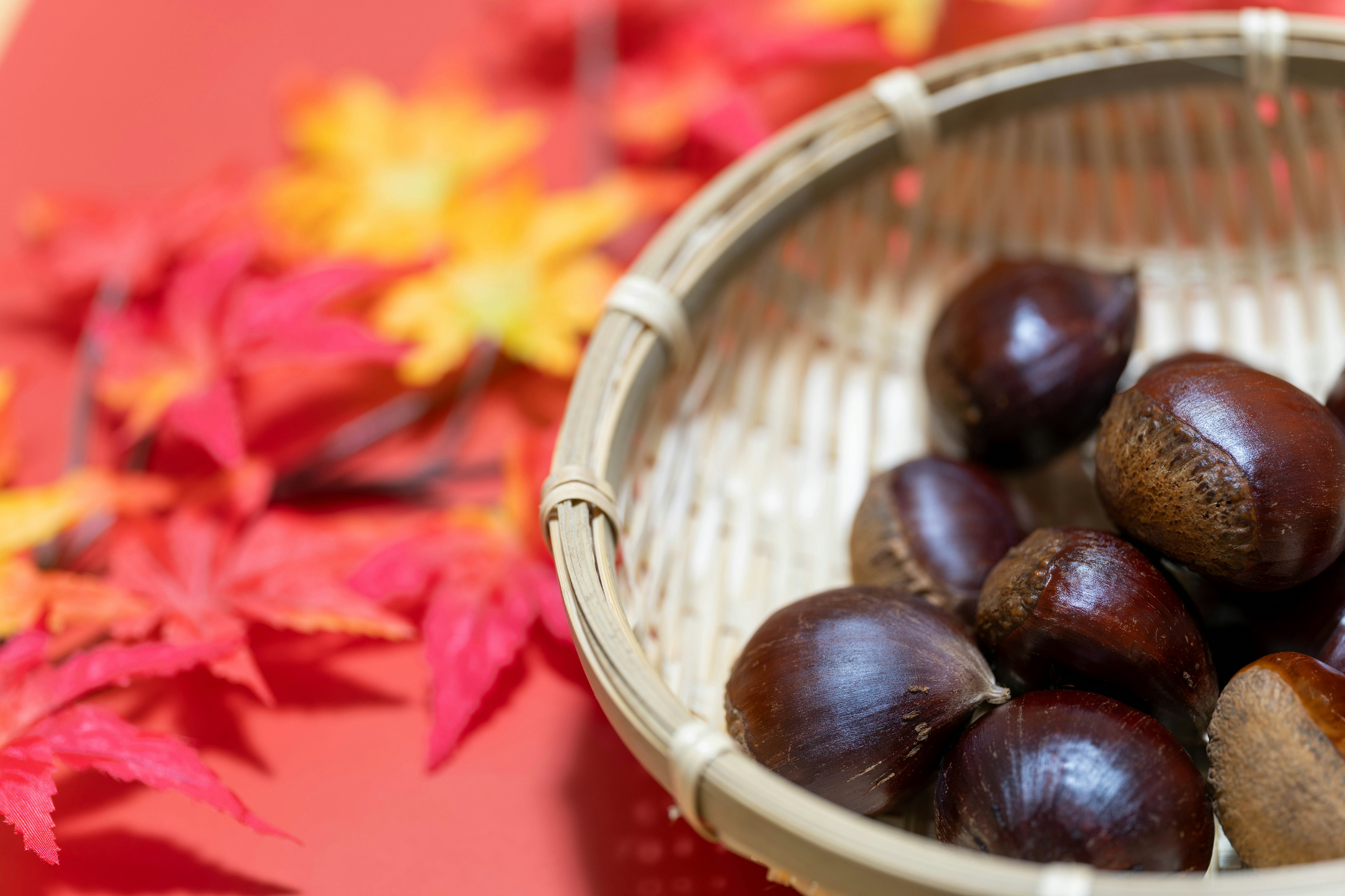 Castagne in un cesto su uno sfondo rosso con foglie autunnali