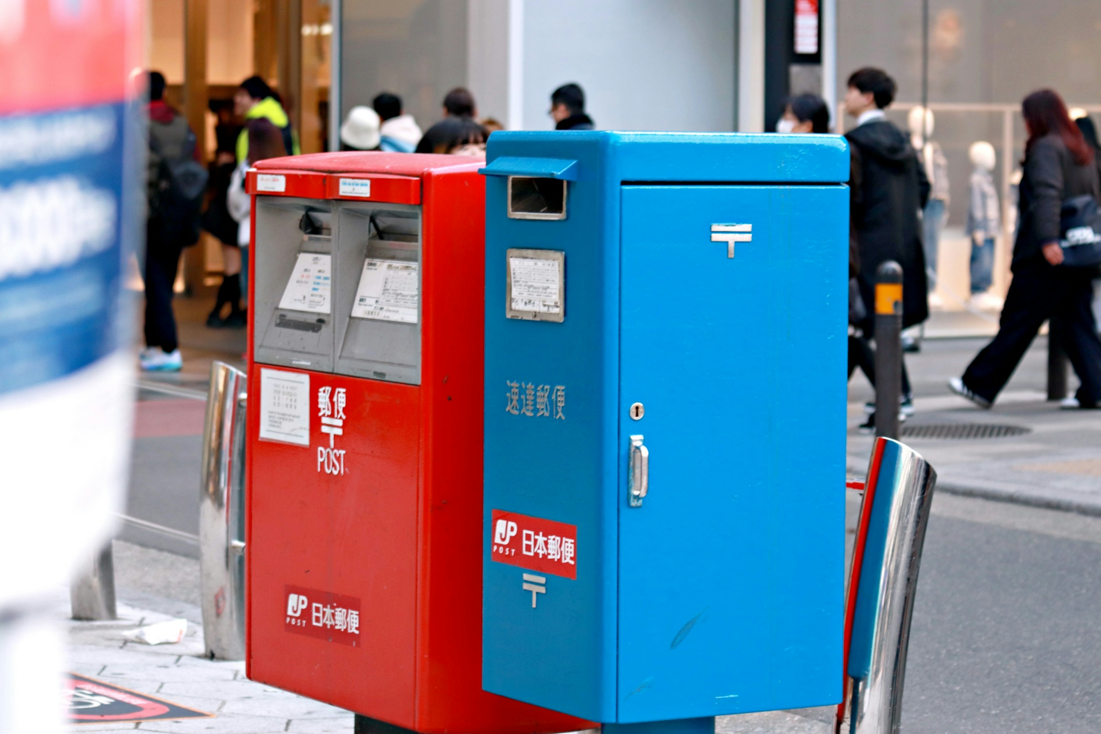 Red and blue mailboxes located on a street corner