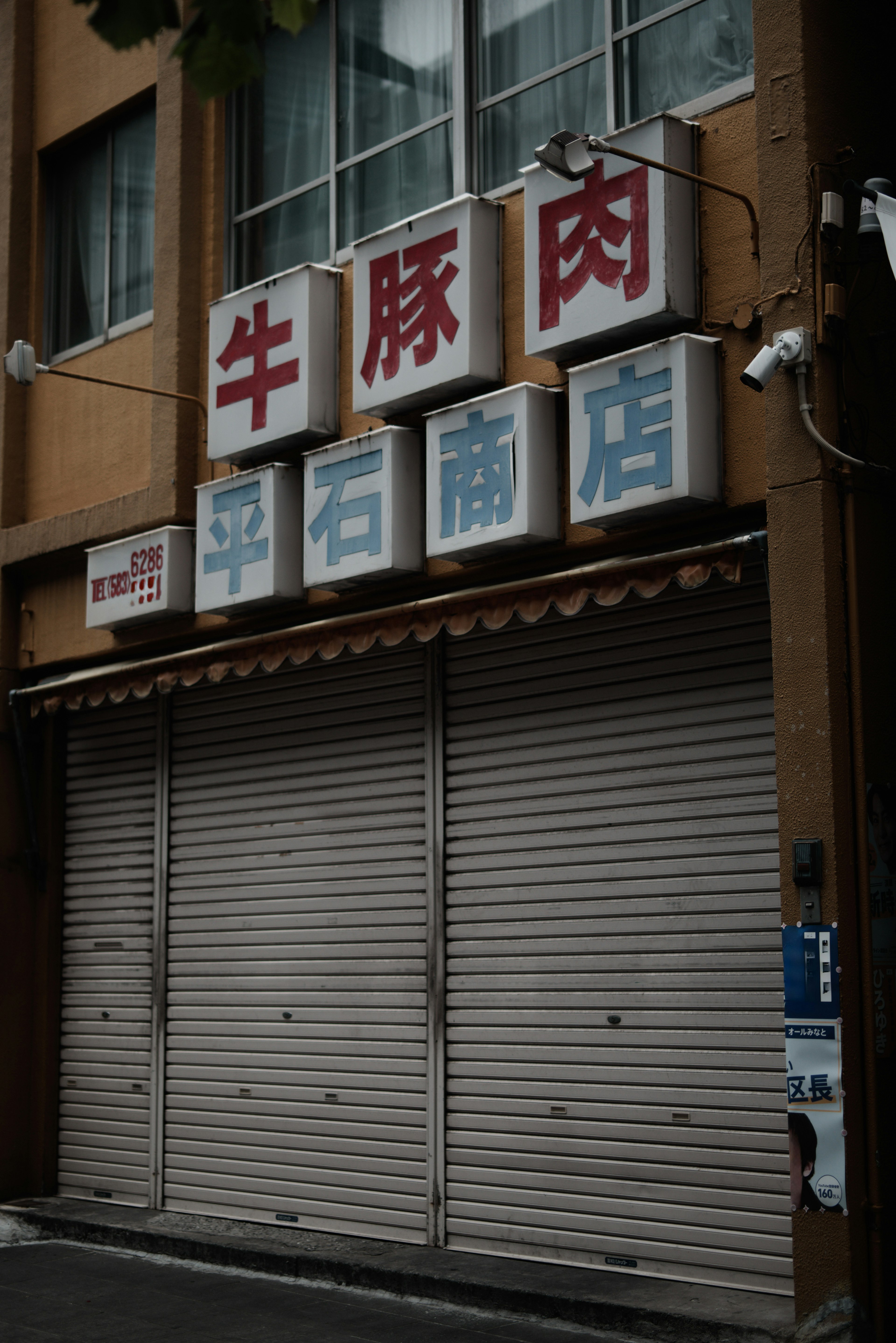 Closed meat shop with signs on the shutter