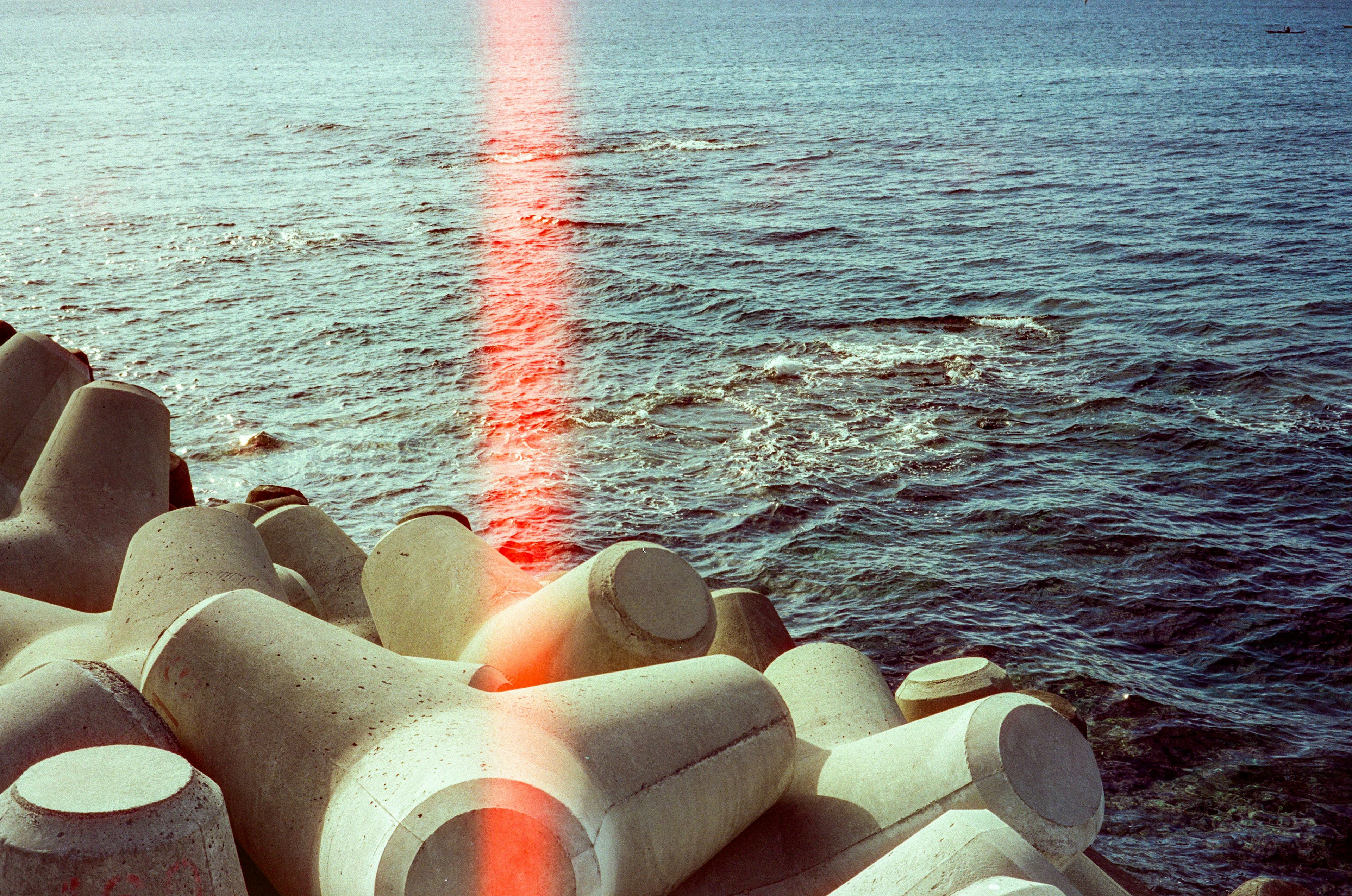 Concrete tetrapods along the shoreline with a red light beam