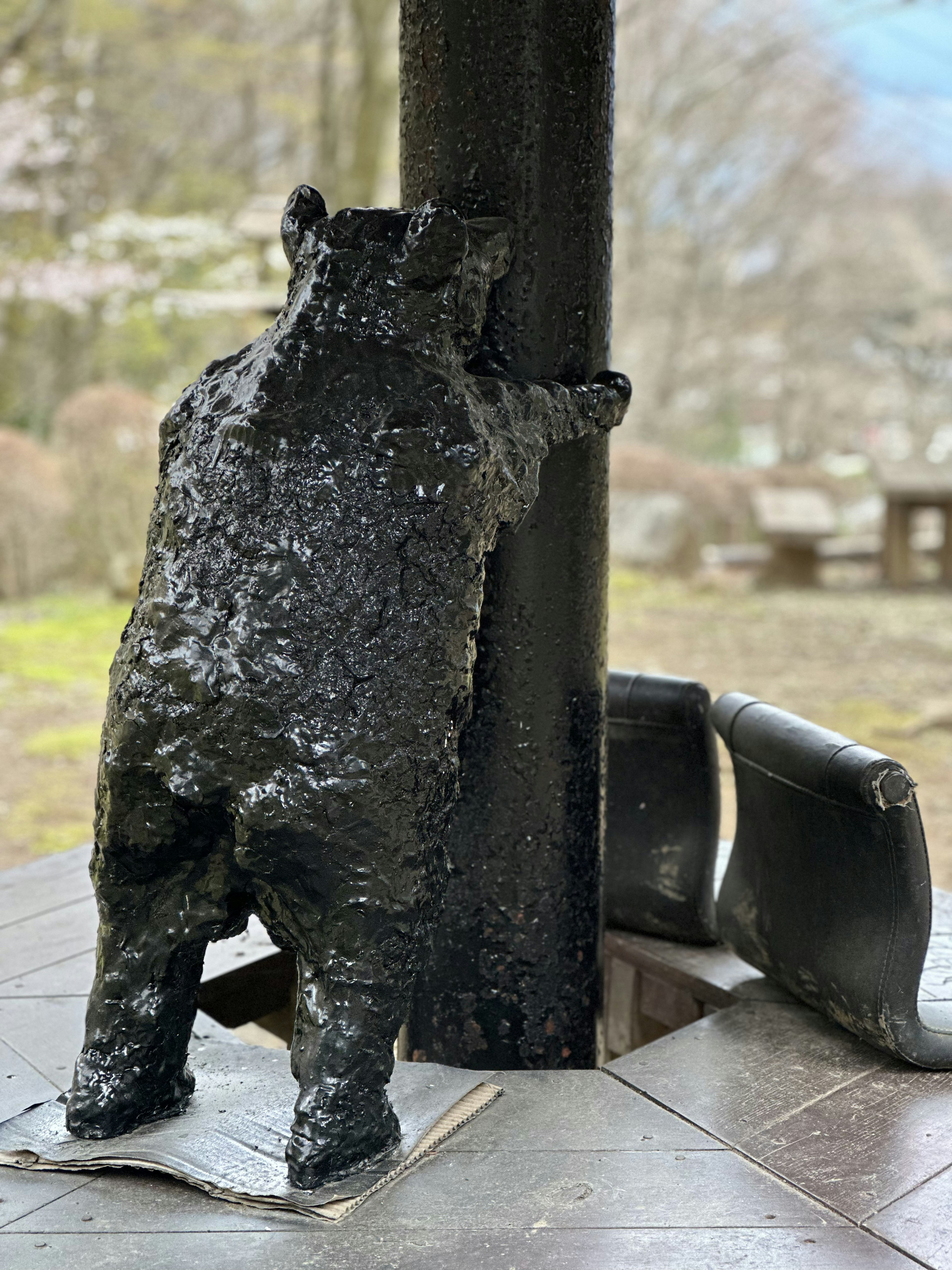 Eine schwarze Bärenskulptur, die an einer Säule in einer malerischen Außenszene lehnt