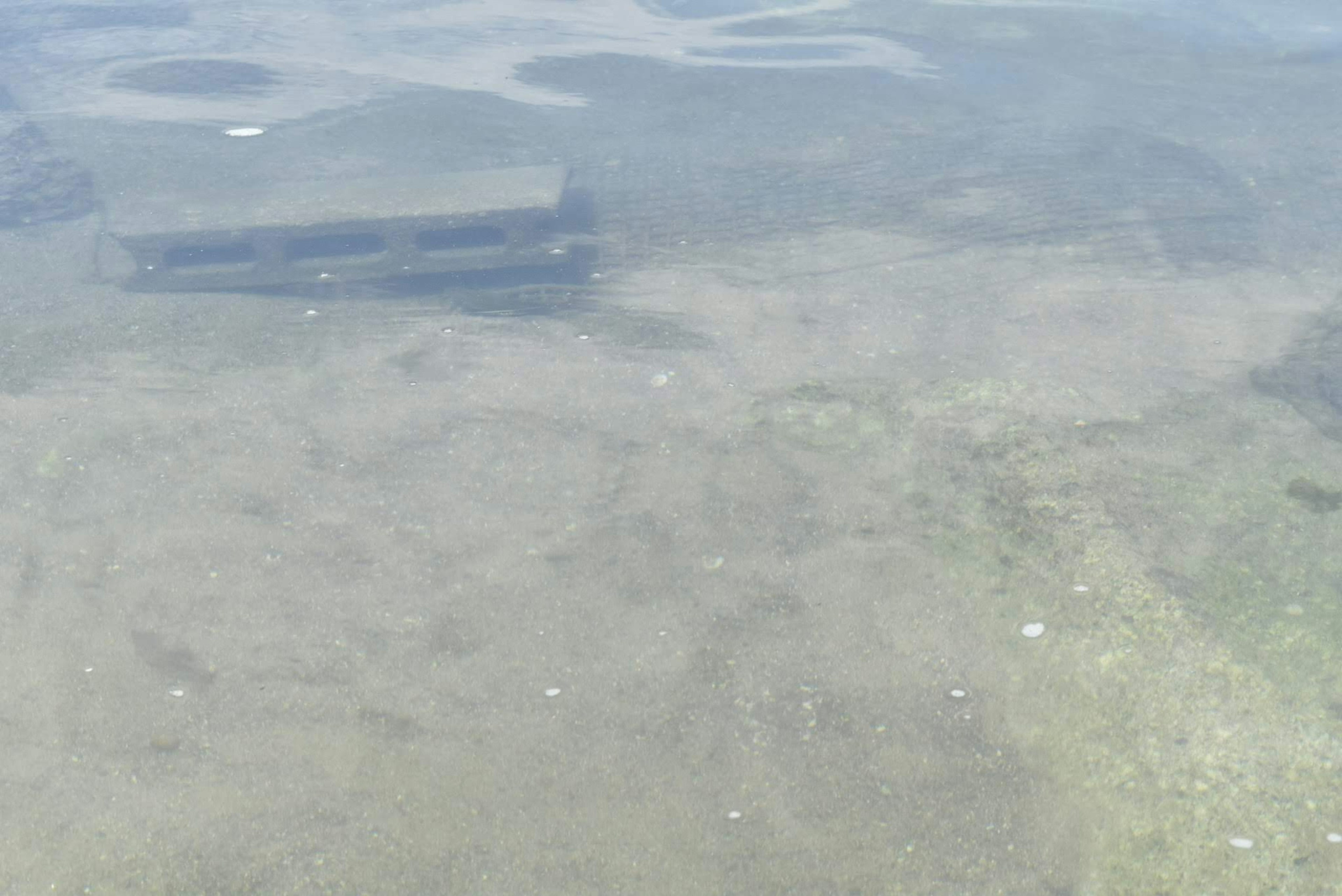 Clear water revealing sandy bottom with small stones