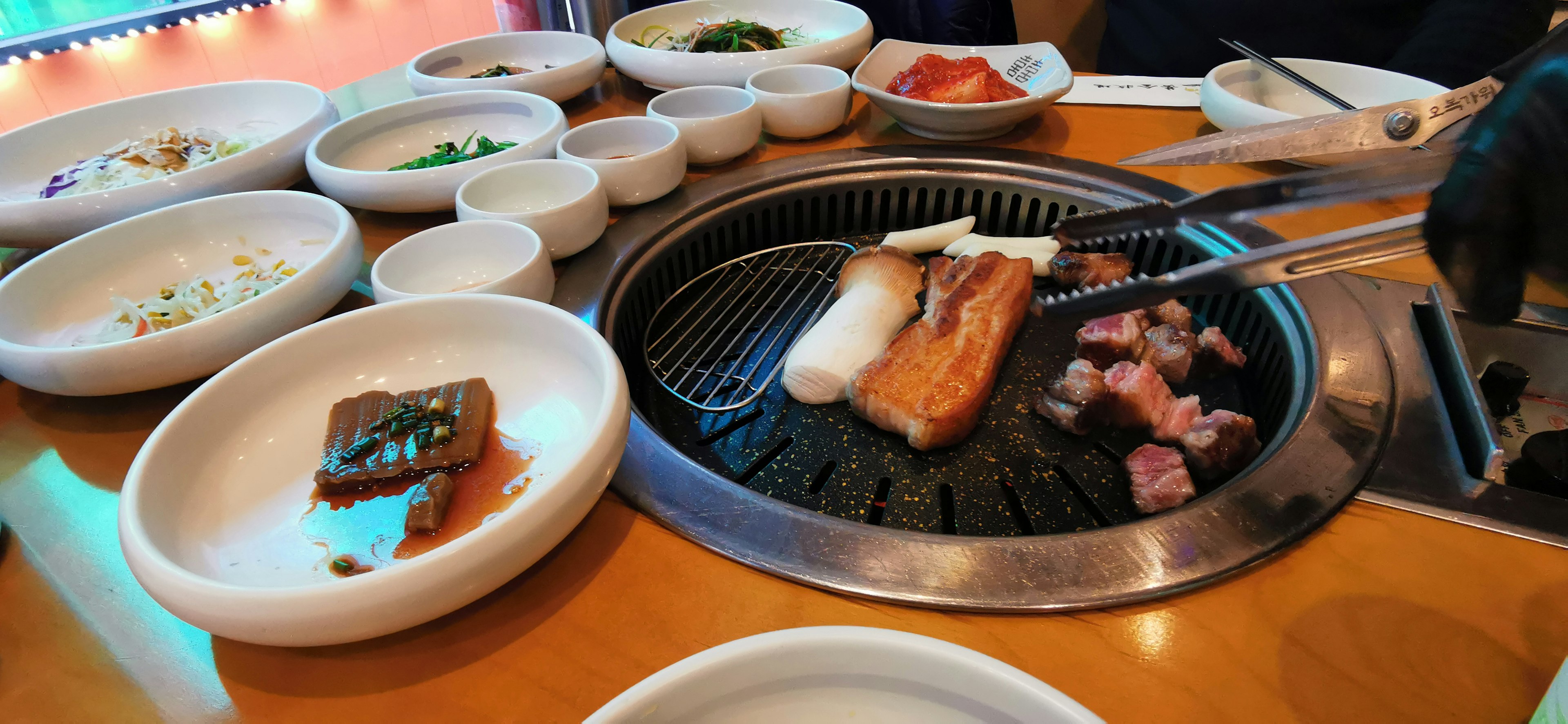 Table scene with grilling pork and vegetables on a barbecue grill