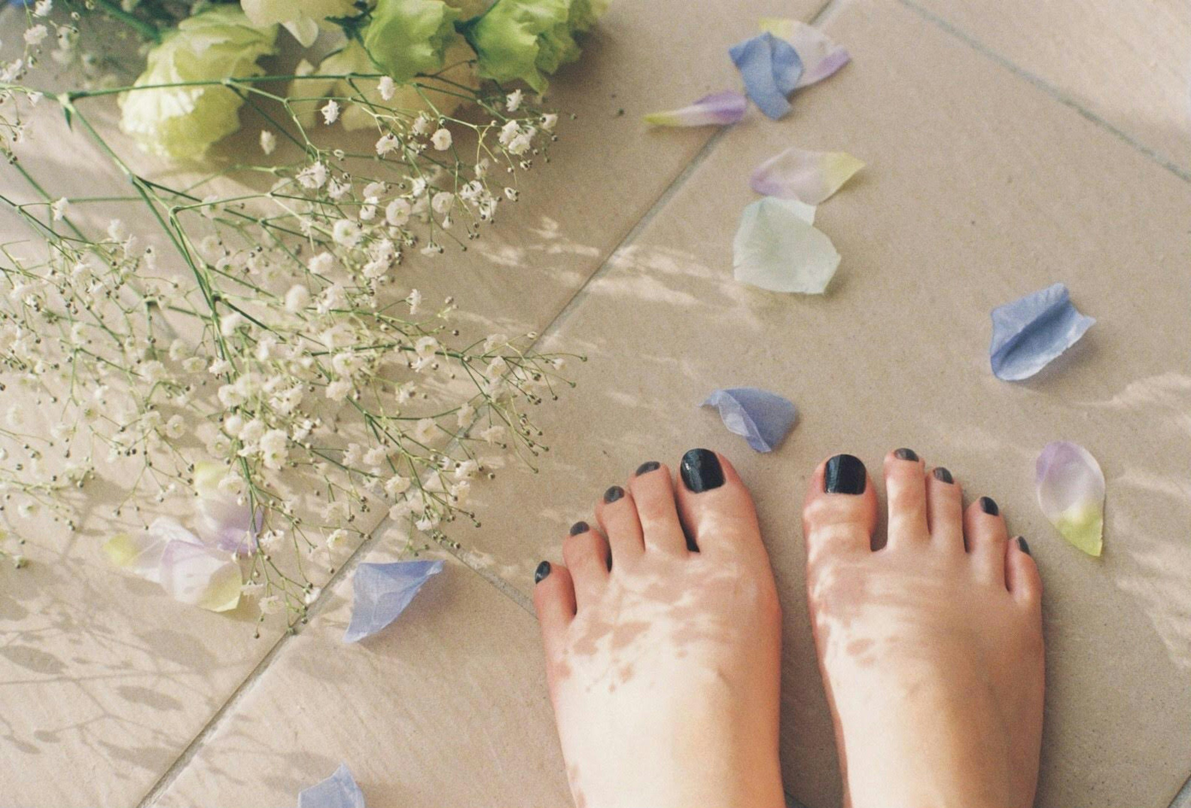 Pies descalzos sobre un suelo suave rodeados de pétalos de flores y pequeñas flores