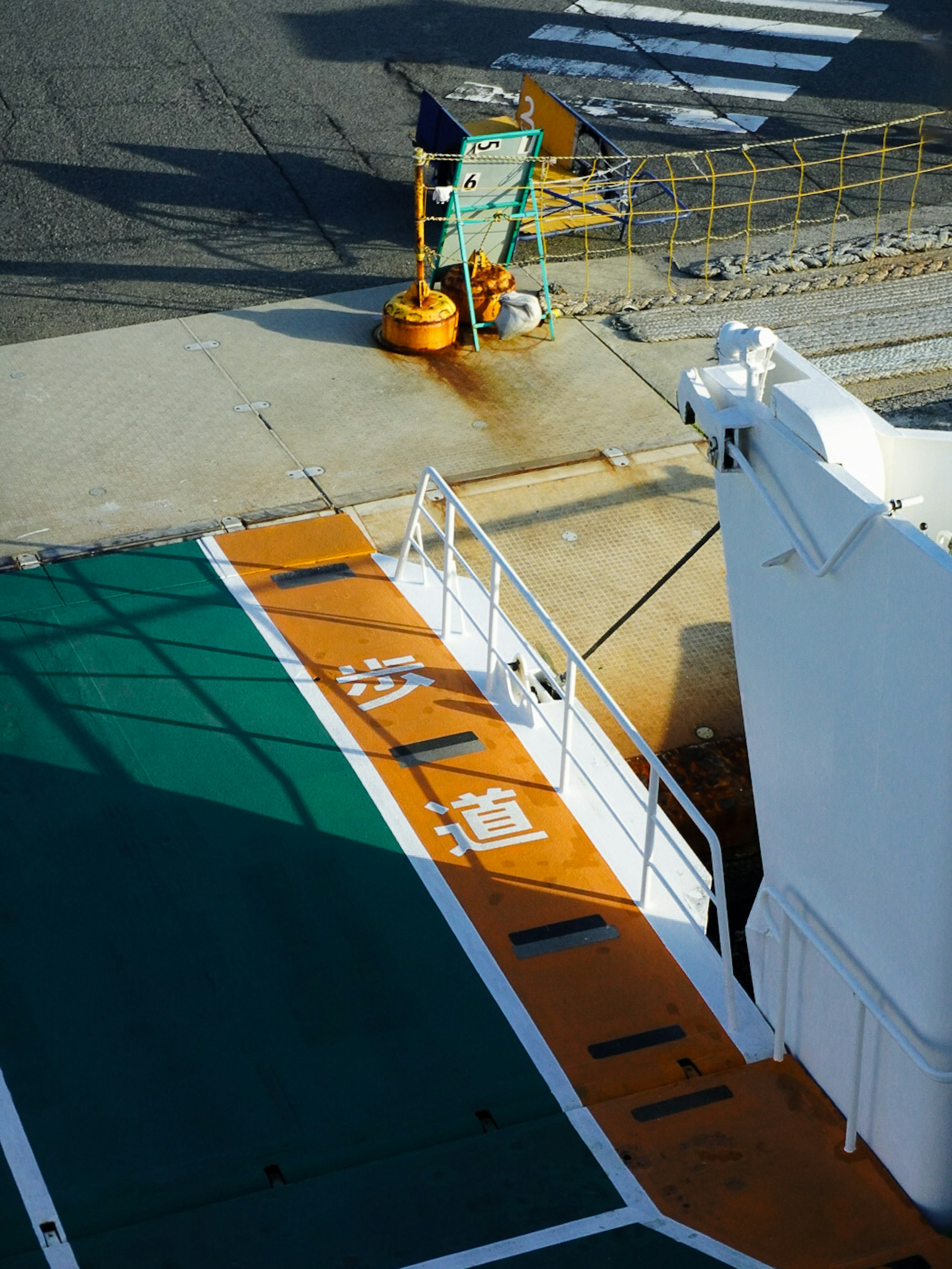 Teil eines Schiffsdecks mit grünen und orangefarbenen Linien in einem Hafen