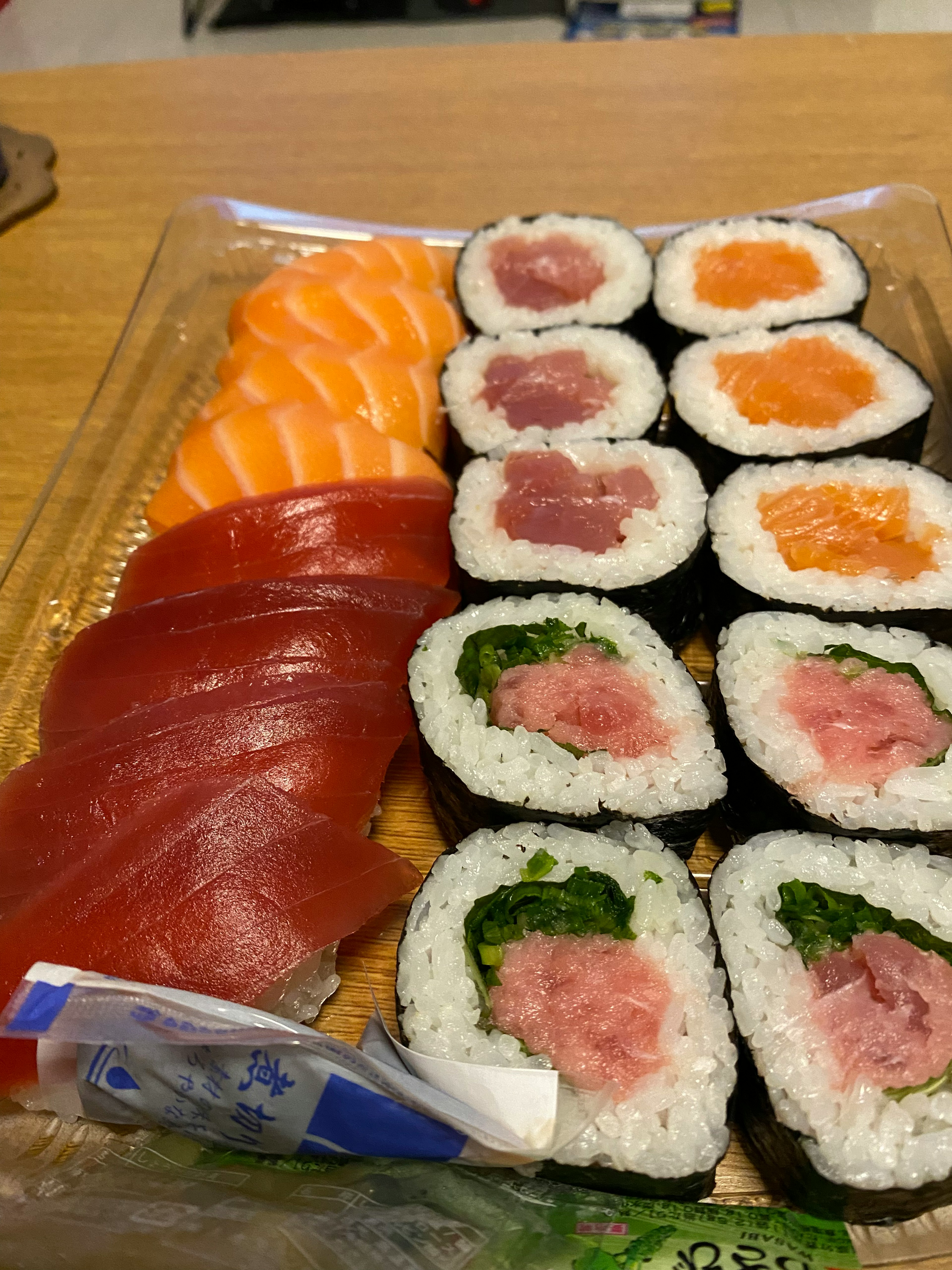 Piring sushi segar dengan sashimi salmon dan tuna serta gulungan maki campuran