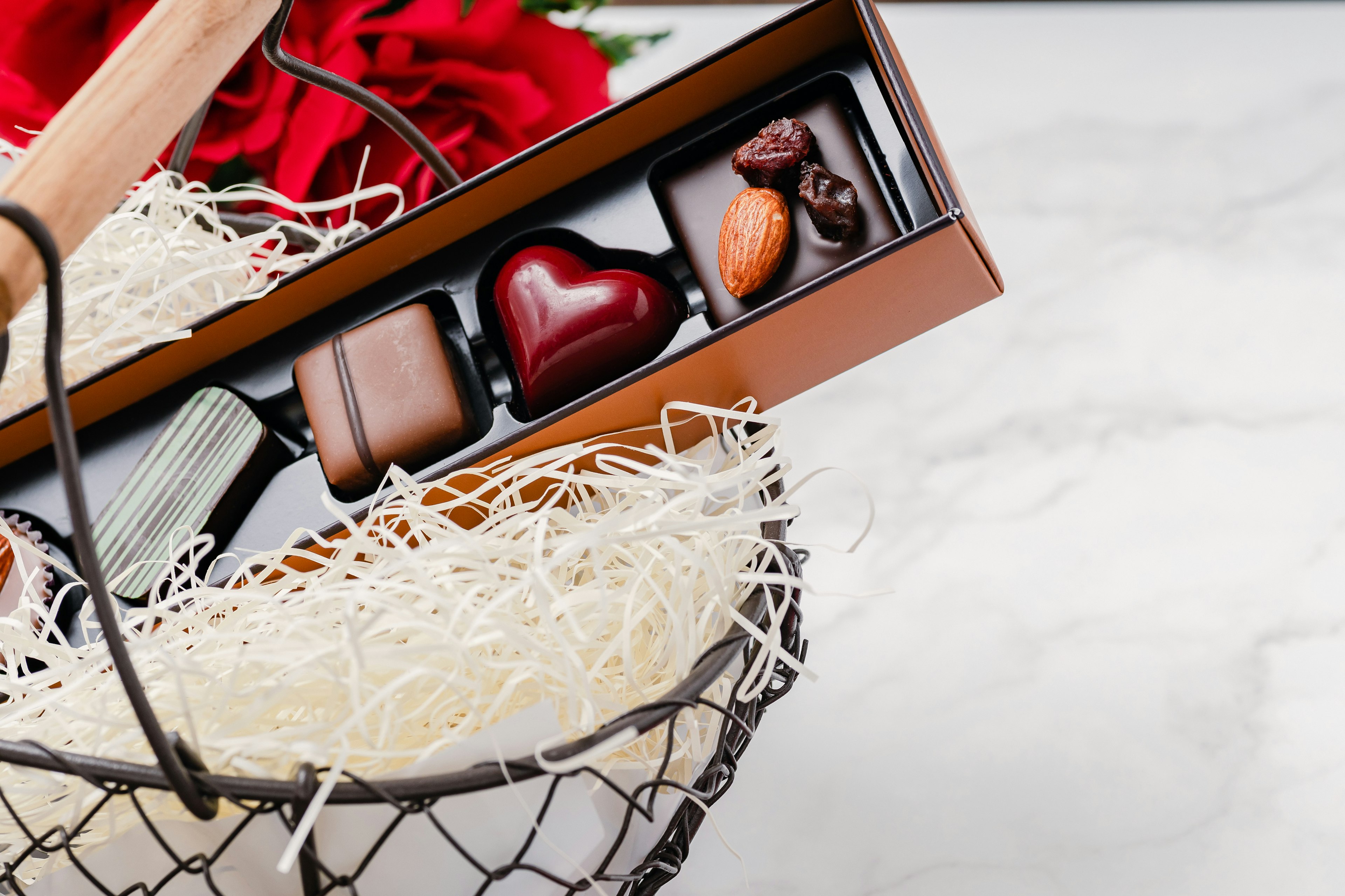 Une belle présentation de roses rouges et de chocolats assortis dans un panier