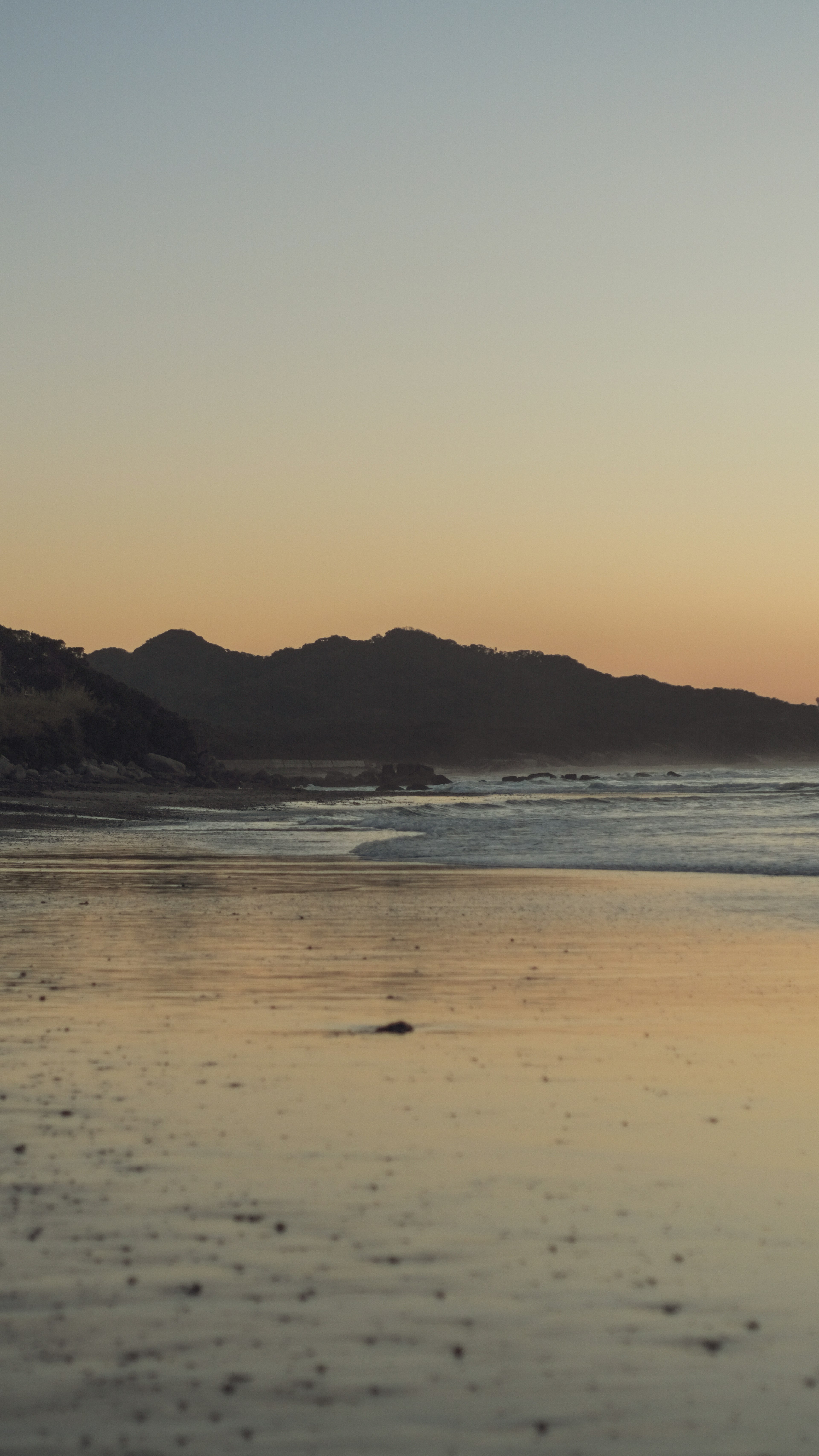 Sunset beach view with silhouettes of mountains