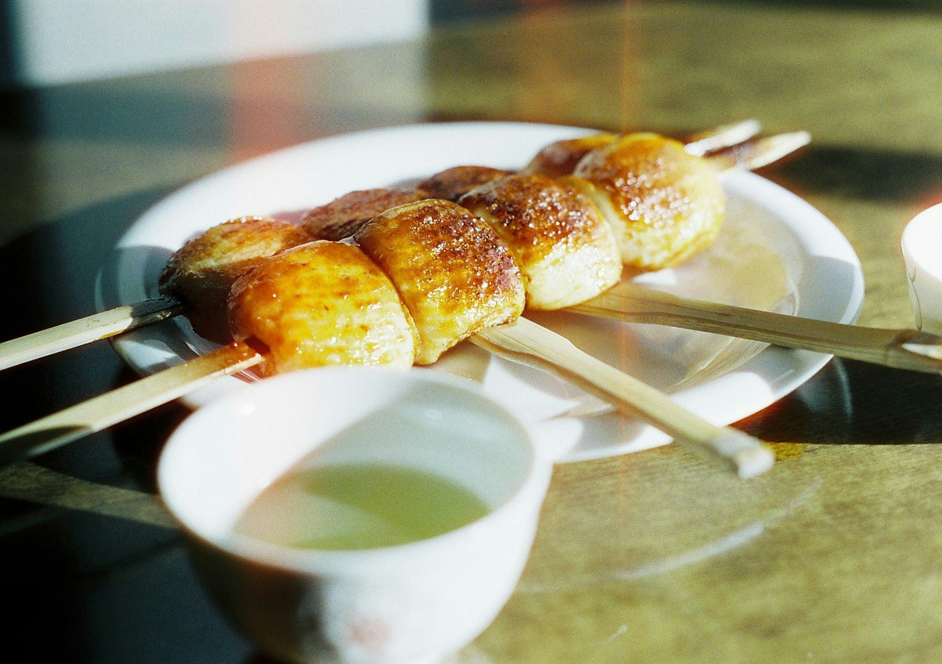 Spiedini di dolci ravioli grigliati su un piatto con una tazza di tè verde