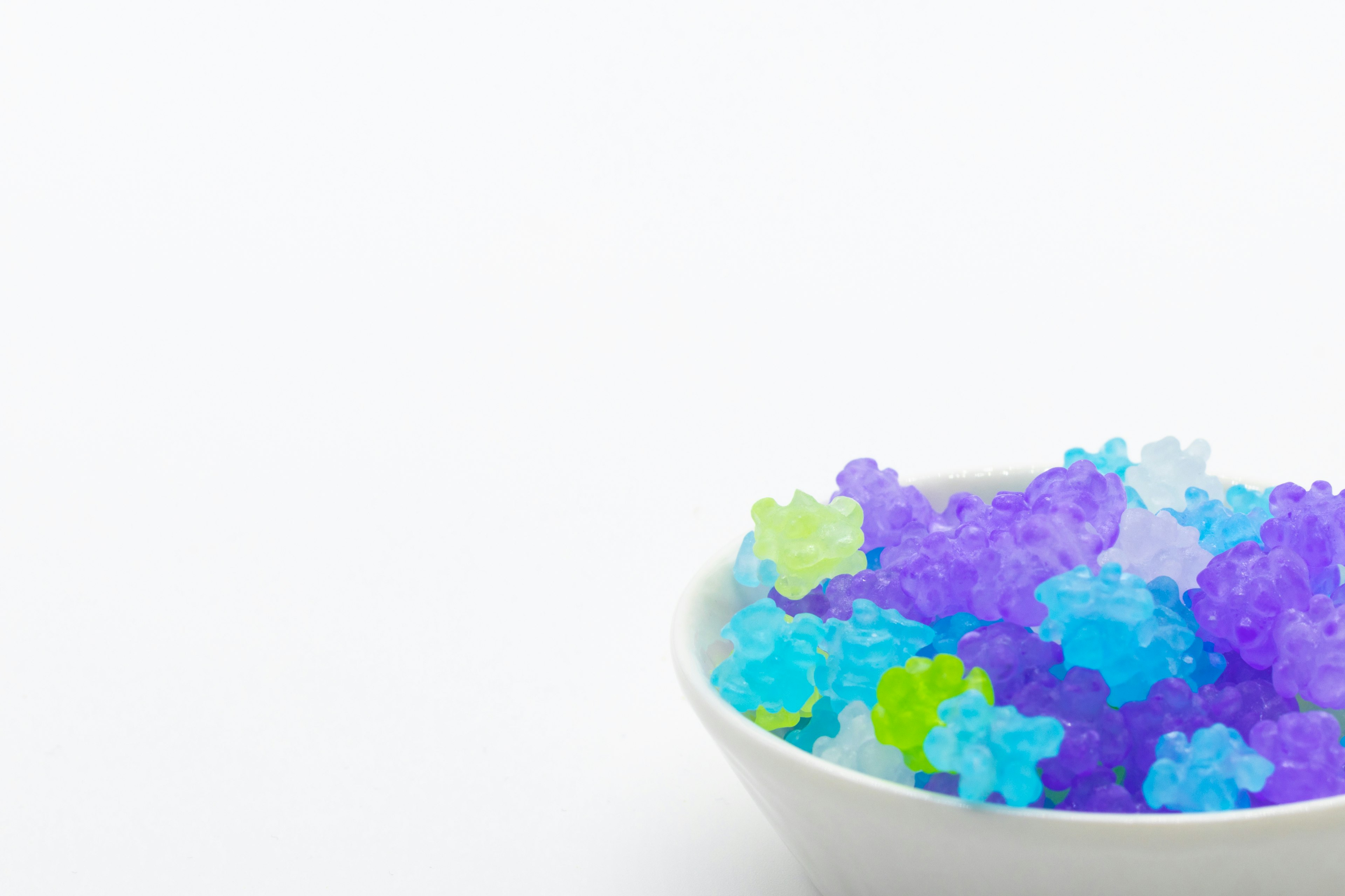 Bowl filled with colorful jelly flowers on a white background