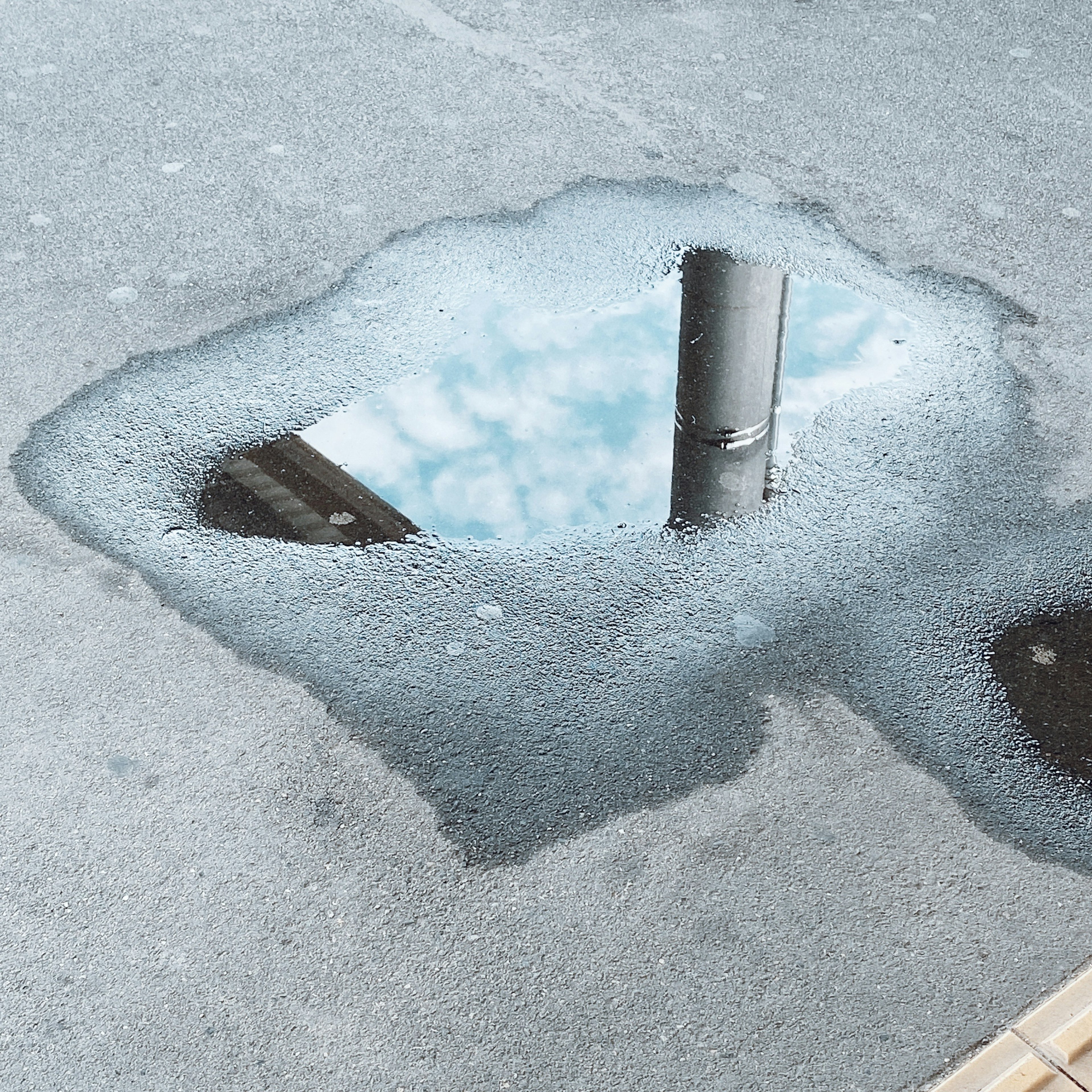 Réflexion du ciel et d'un poteau dans une flaque d'eau