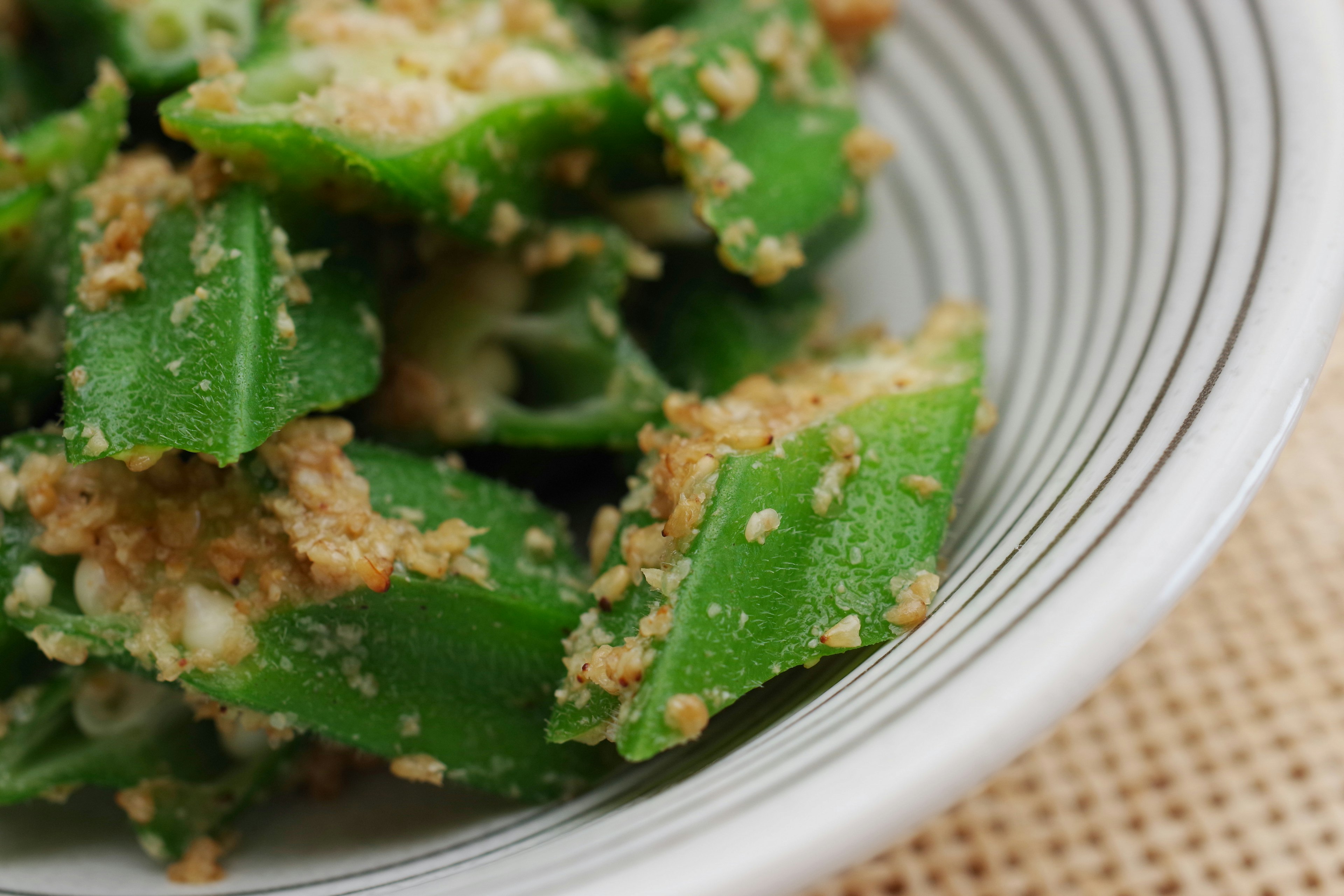 Primo piano di okra verde mescolata con pangrattato in una ciotola