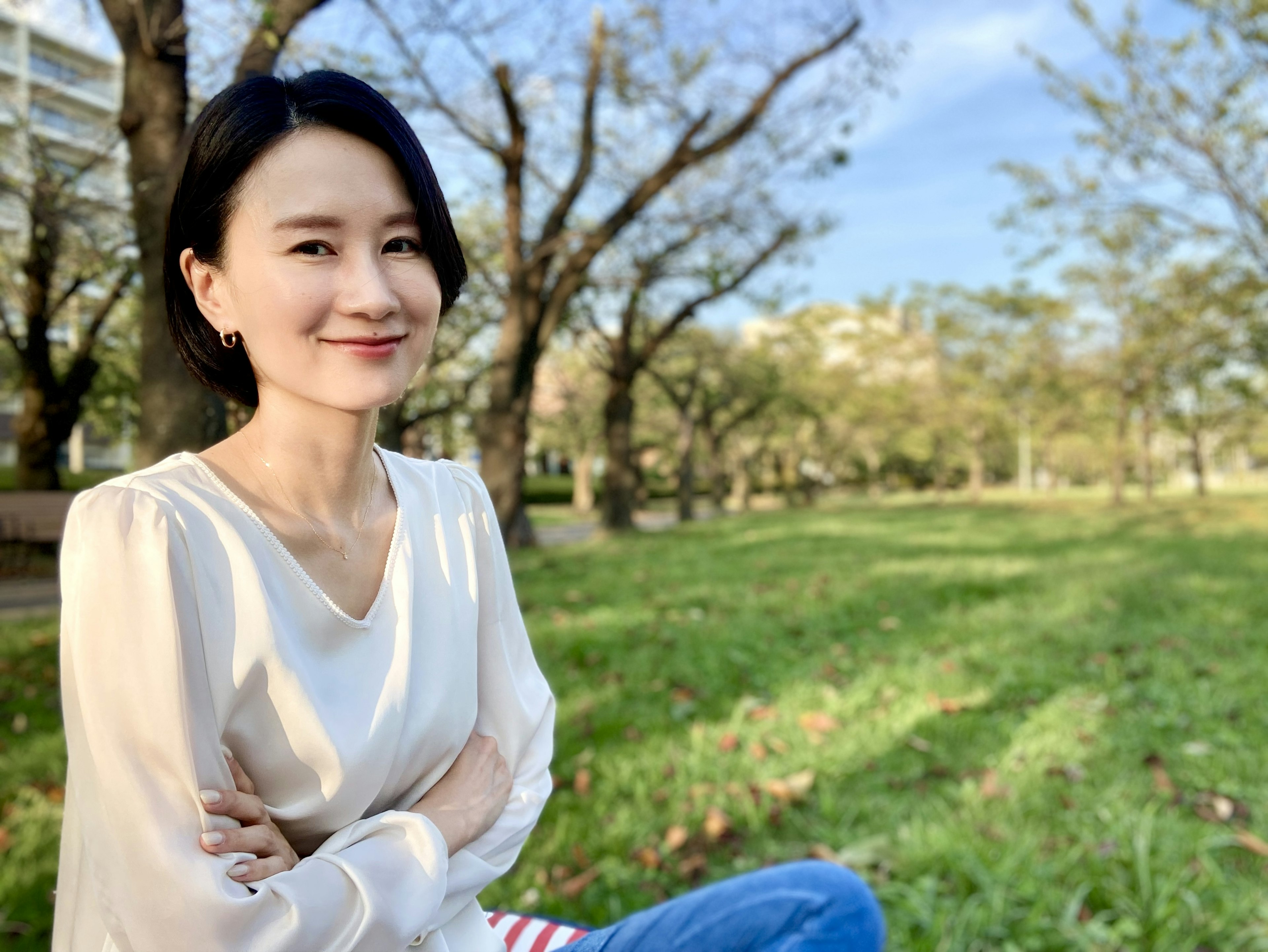 Porträt einer Frau, die auf grünem Gras in einem Park sitzt