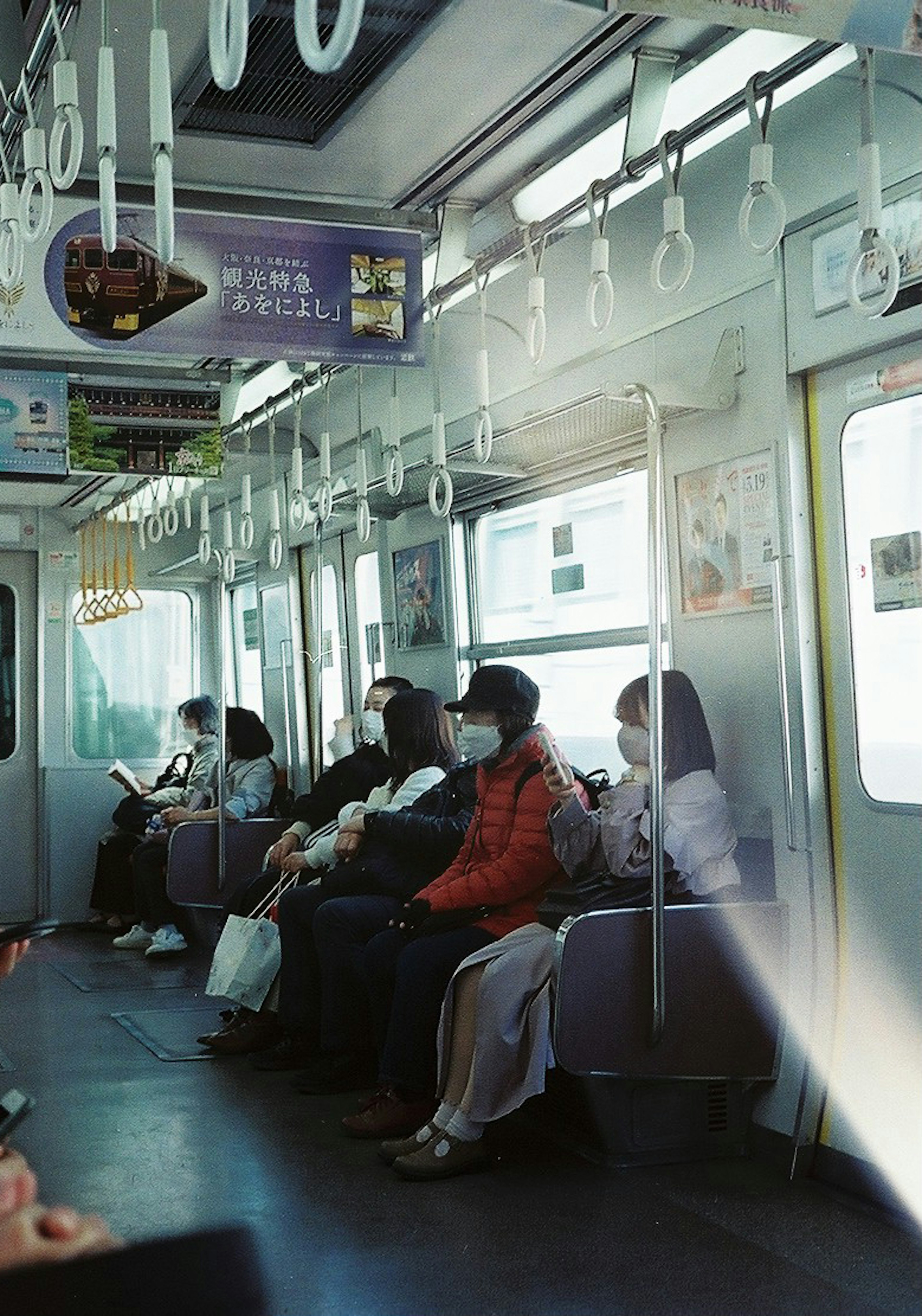 Interior kereta bawah tanah dengan penumpang yang duduk dan pegangan gantung