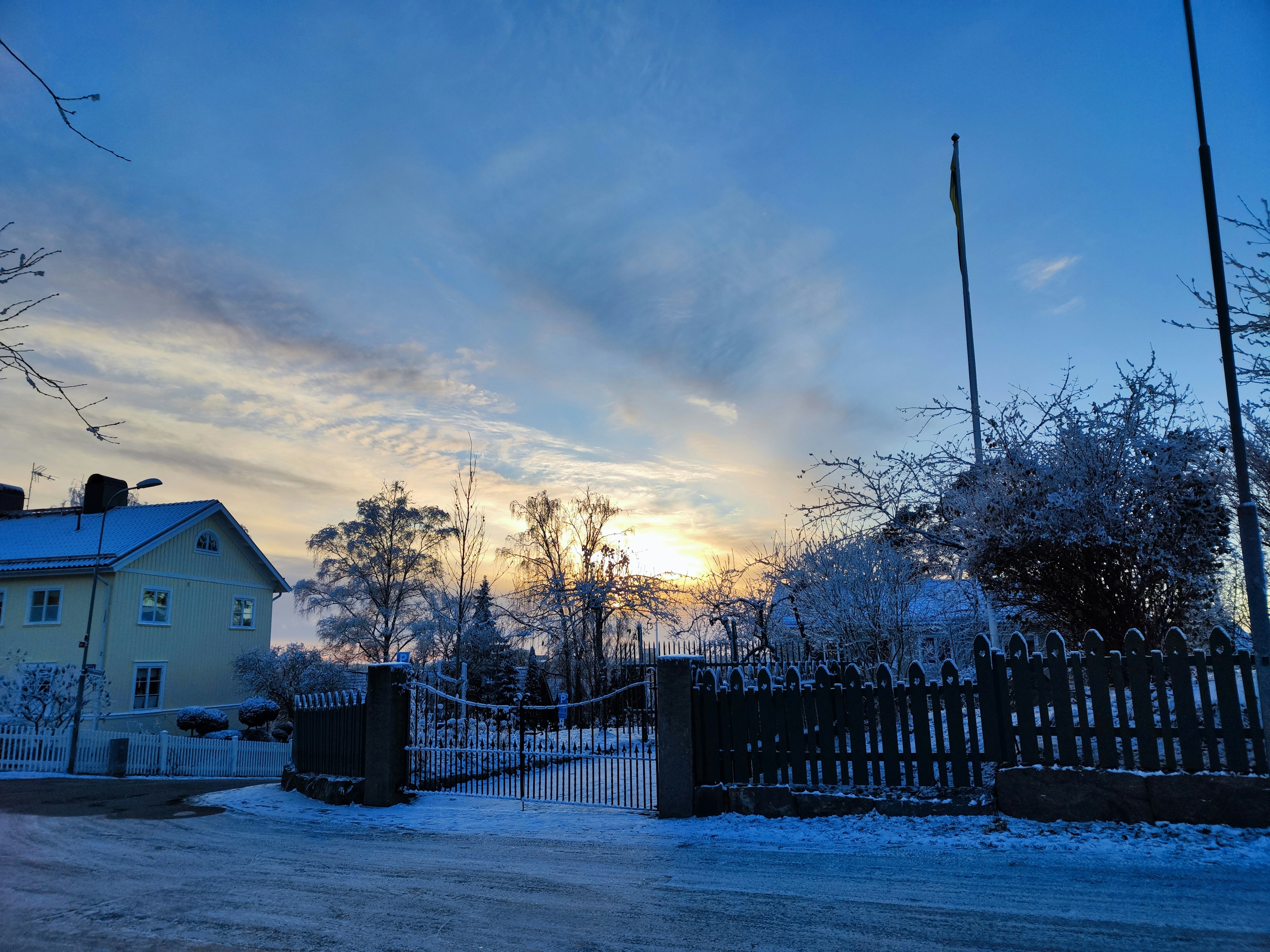 Winterlandschaft mit blauem Himmel gelbes Haus schneebedecktes Tor Sonnenaufgang