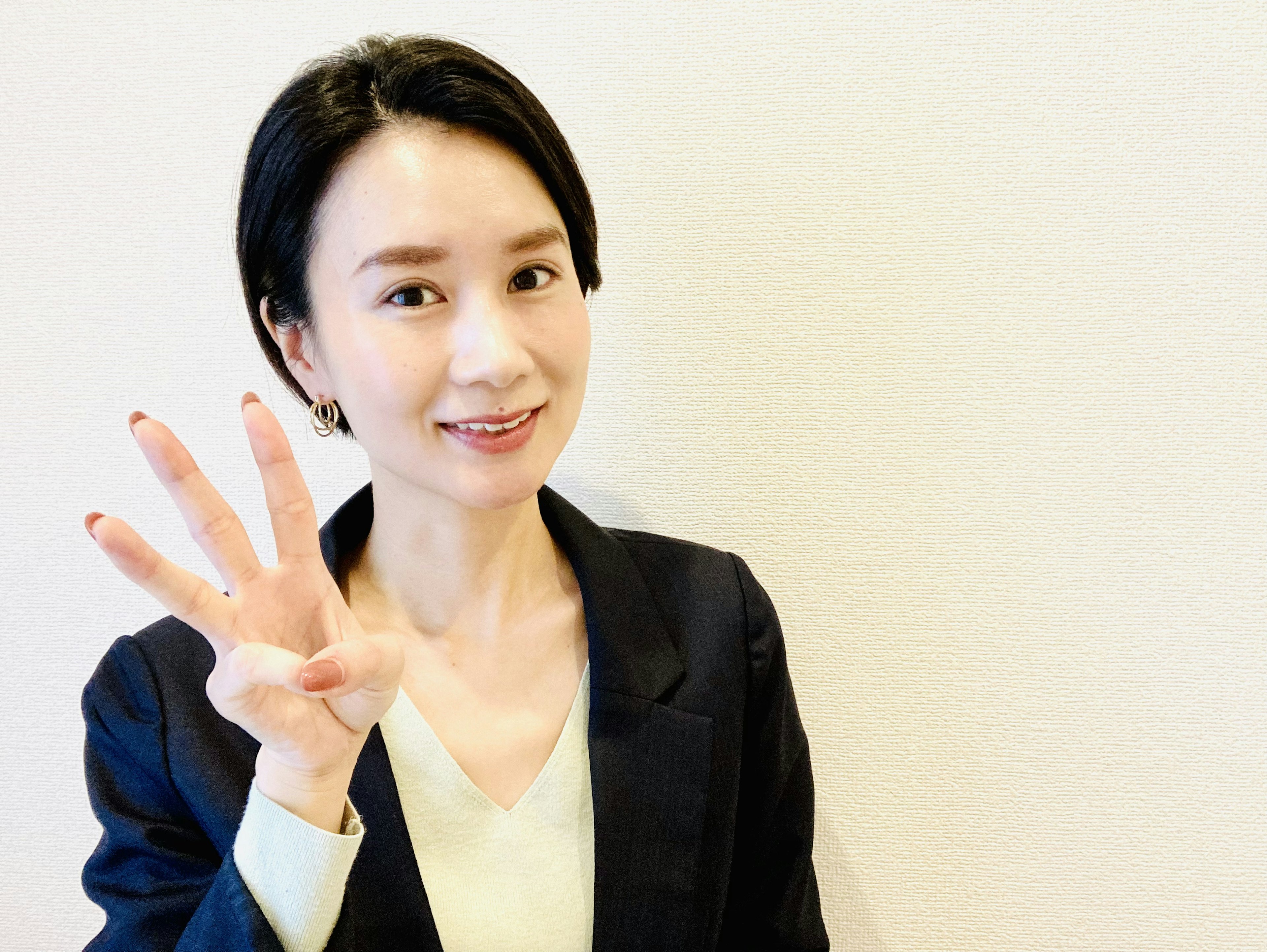 Smiling woman in a suit showing four fingers