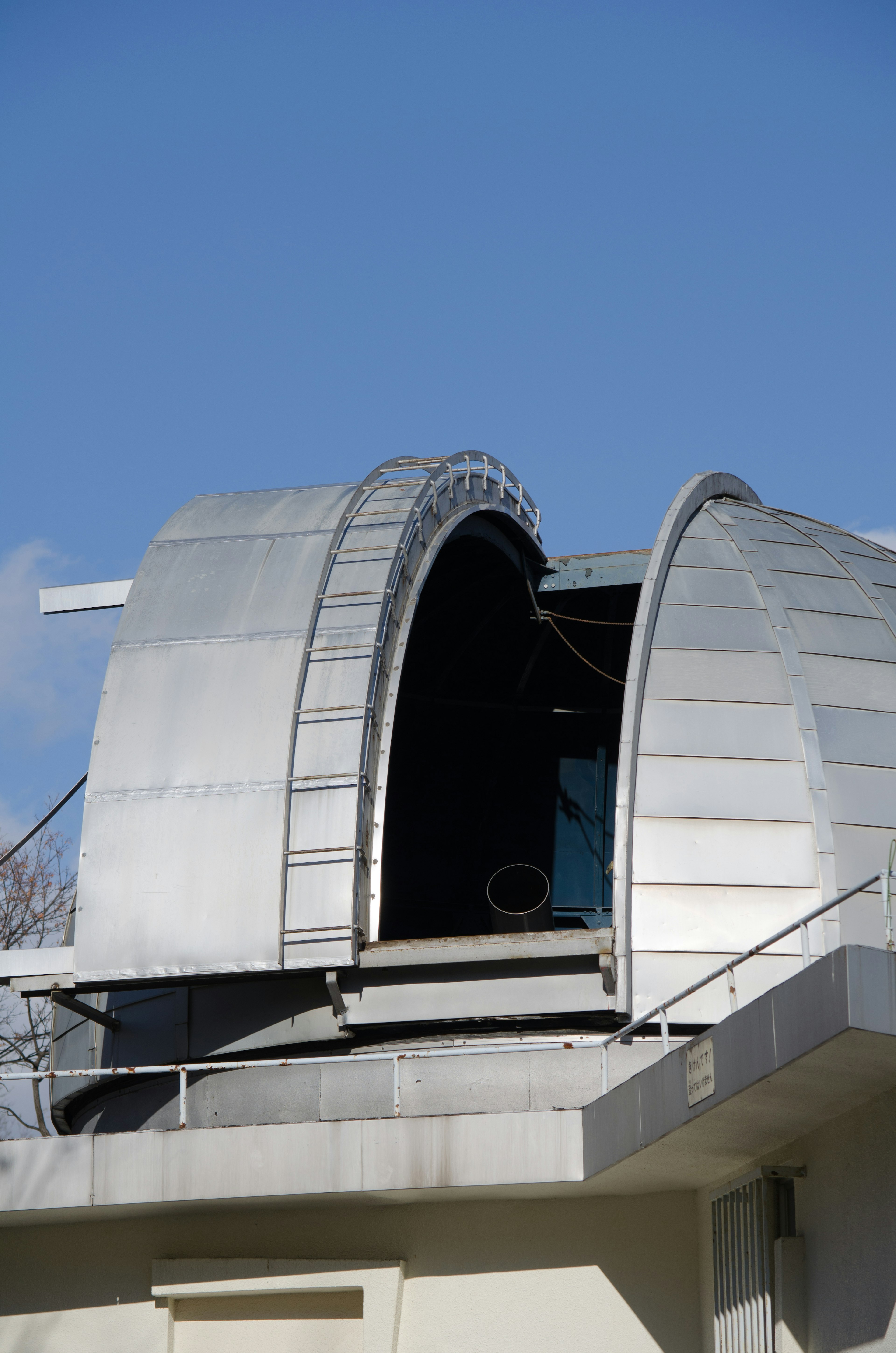 Partie d'un dôme d'observatoire argenté sous un ciel bleu