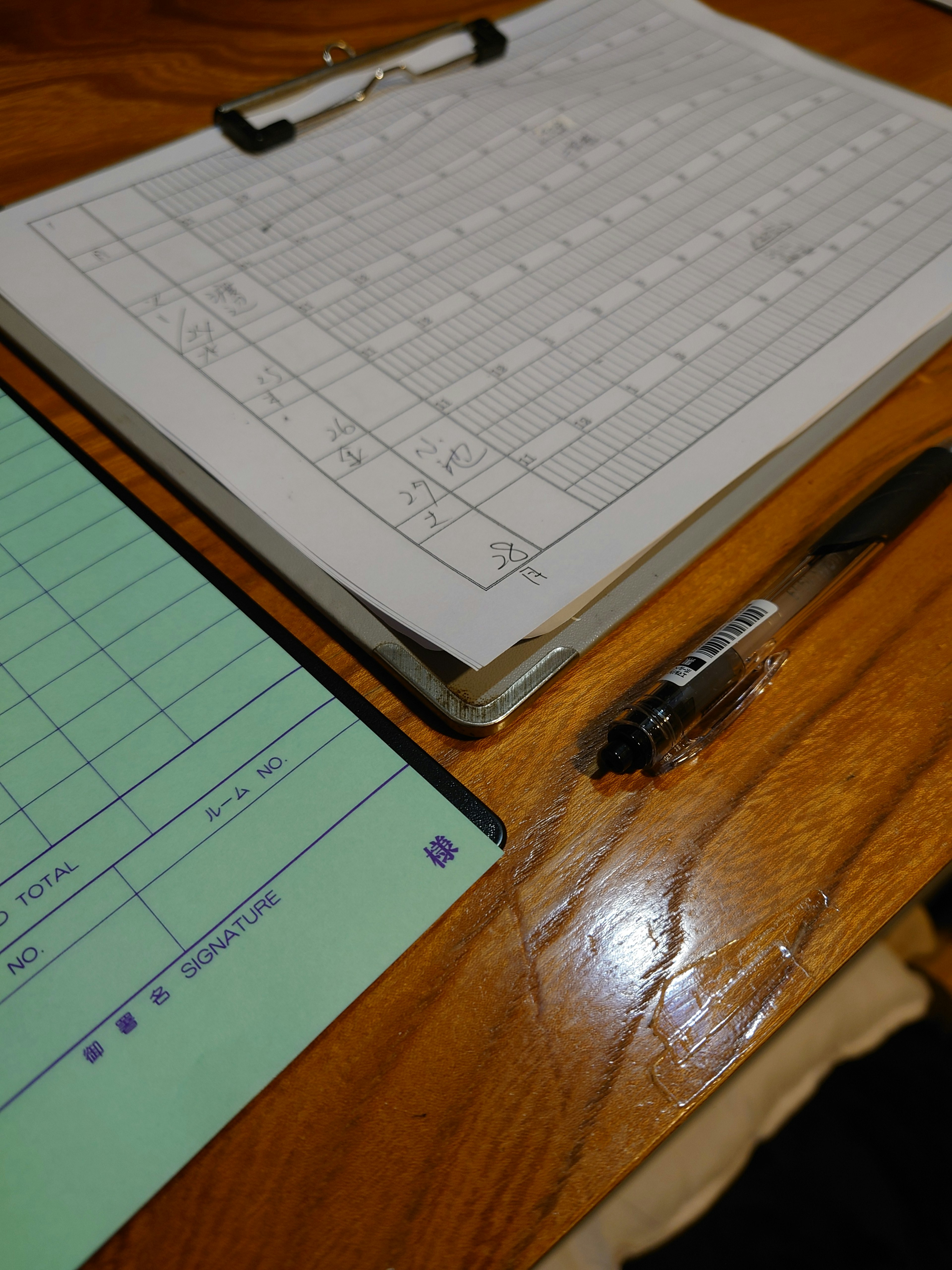 Porte-documents et stylo sur une table en bois papiers verts et blancs disposés