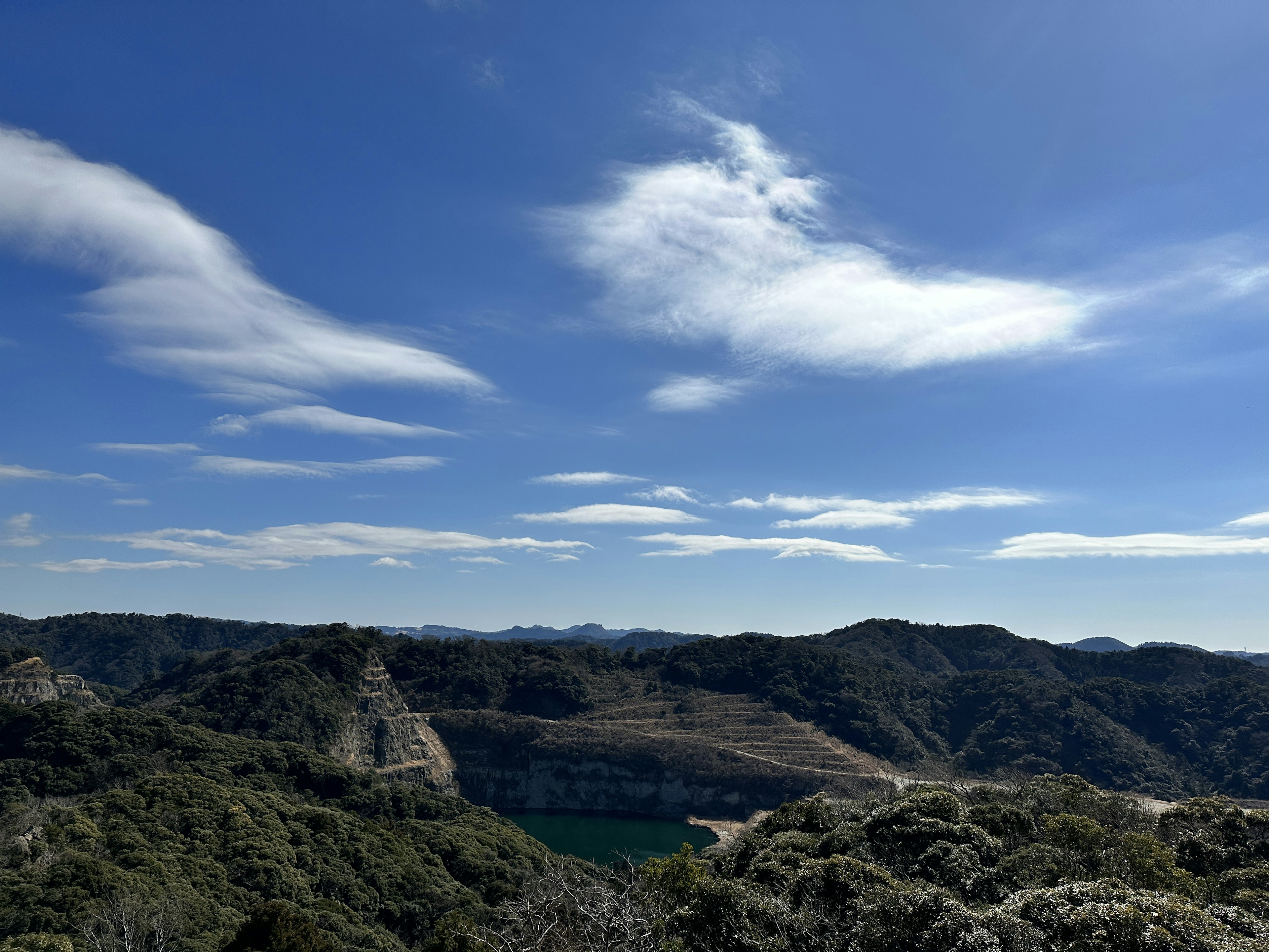 Vista escénica de montañas y un lago bajo un cielo azul con nubes blancas