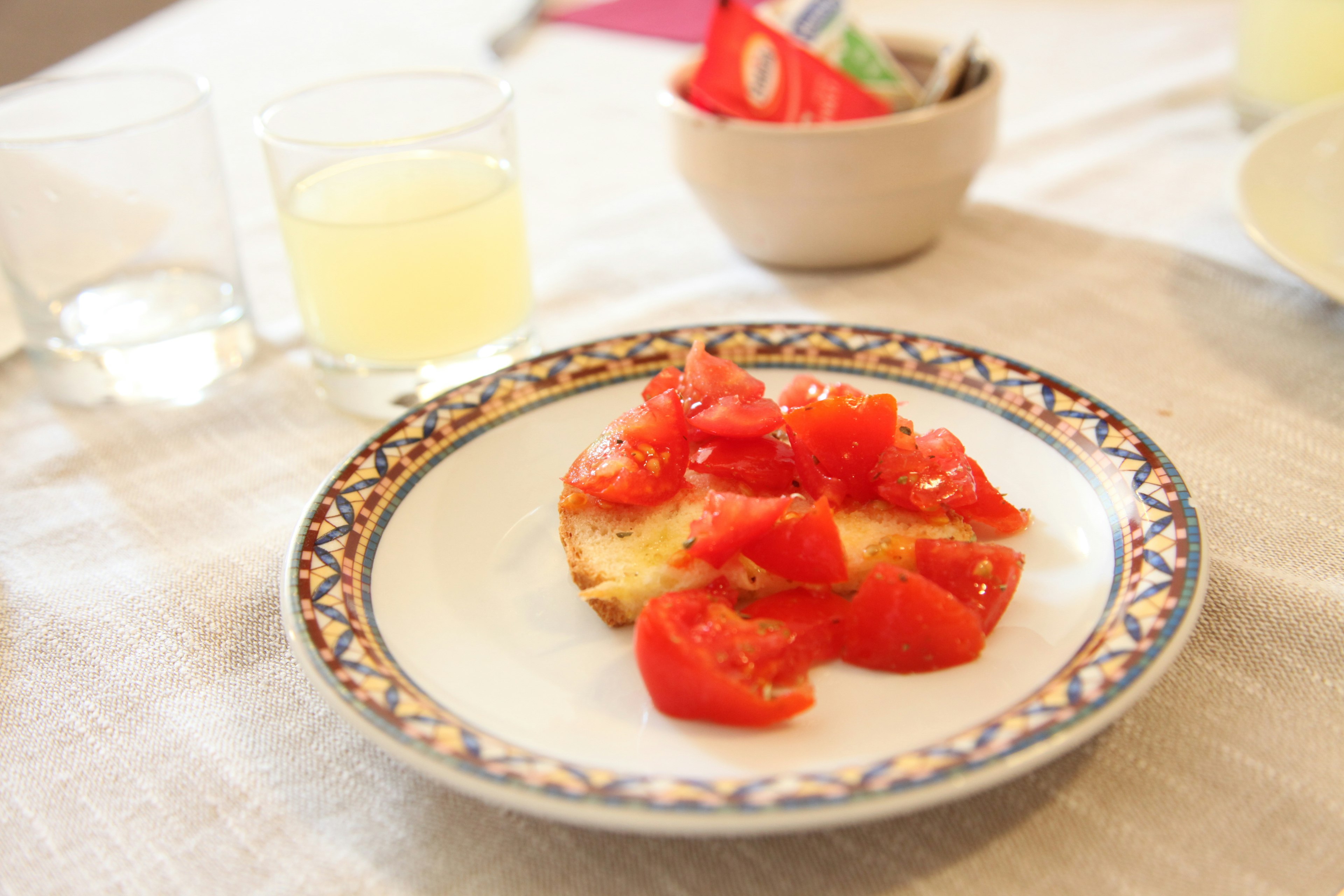 Piatto con pane guarnito di pomodori tritati e bicchieri di bevande