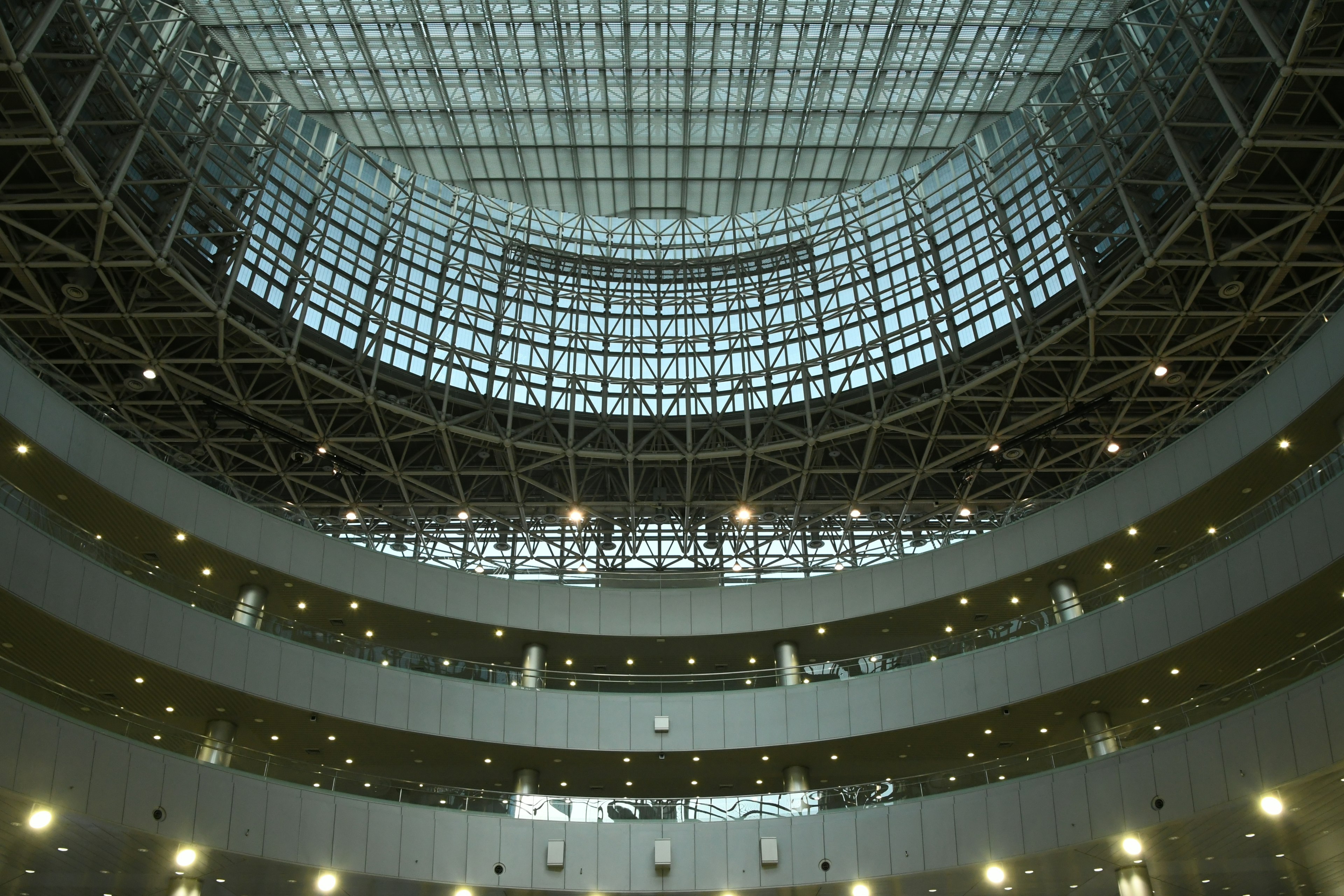 Interior bangunan modern dengan struktur melingkar atap kaca dan pencahayaan cerah