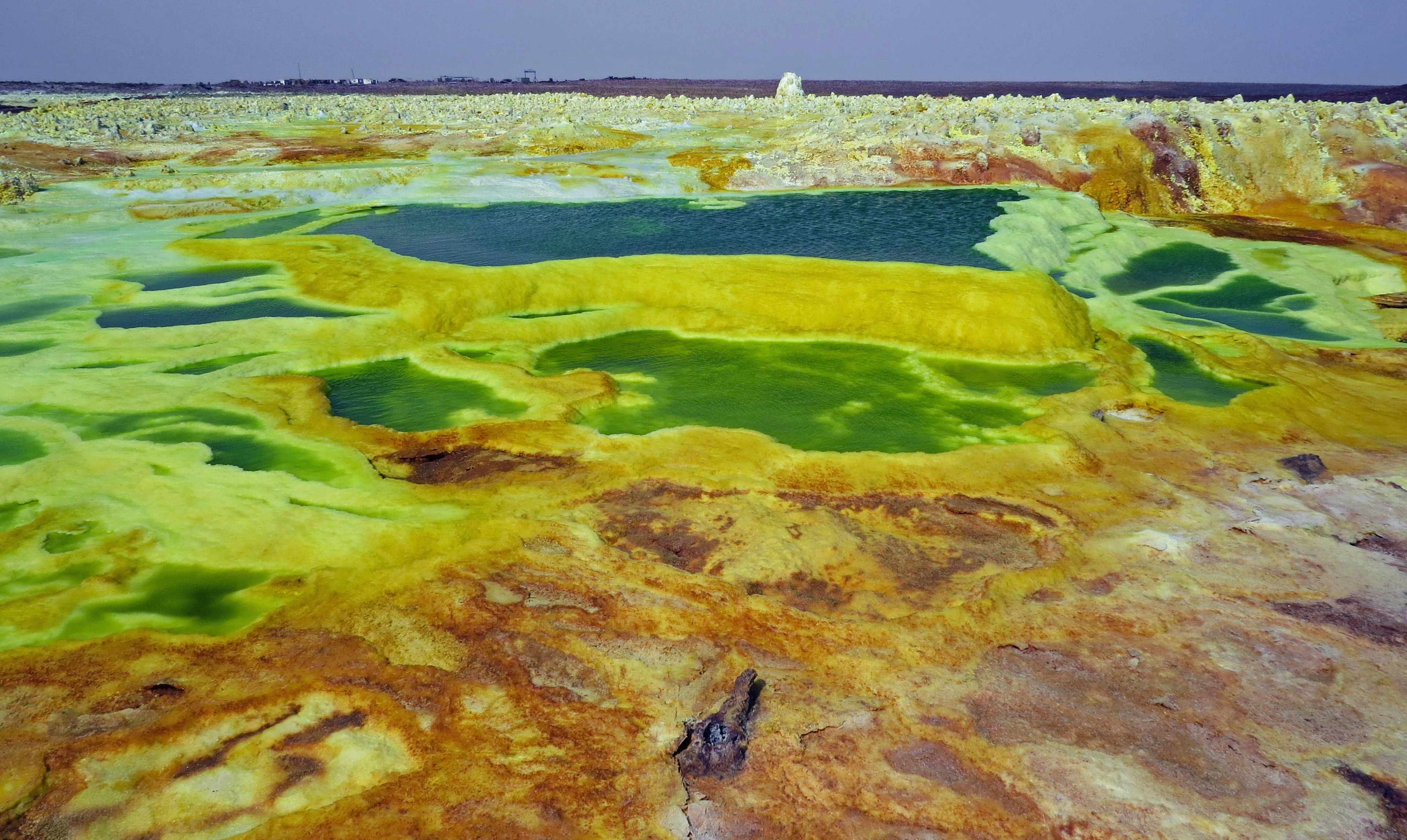 Danau hijau cerah dikelilingi formasi mineral kuning