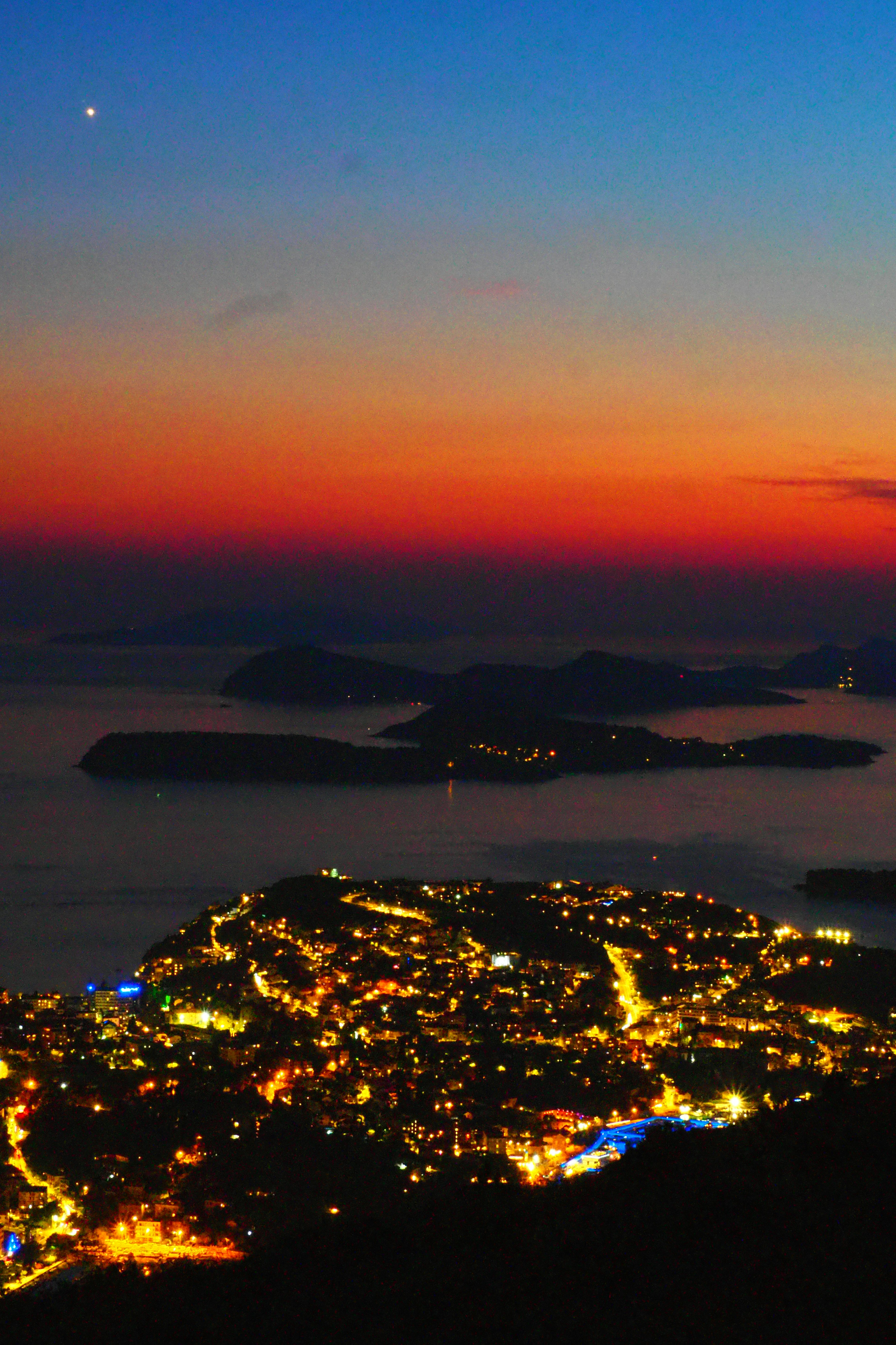 Vista nocturna de la ciudad con cielo al atardecer y océano al fondo