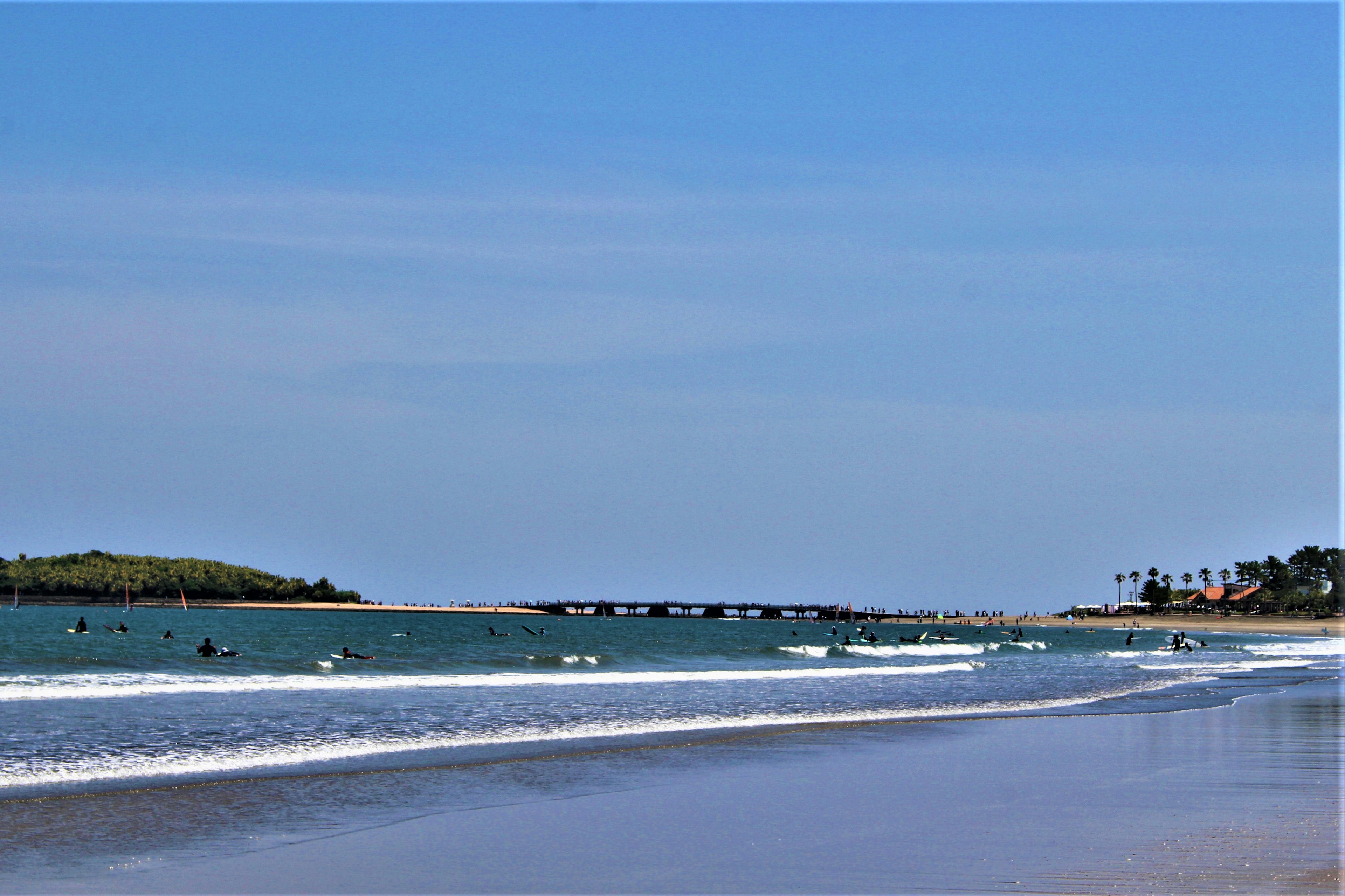 Vista panoramica della spiaggia con mare blu e surfisti che si divertono