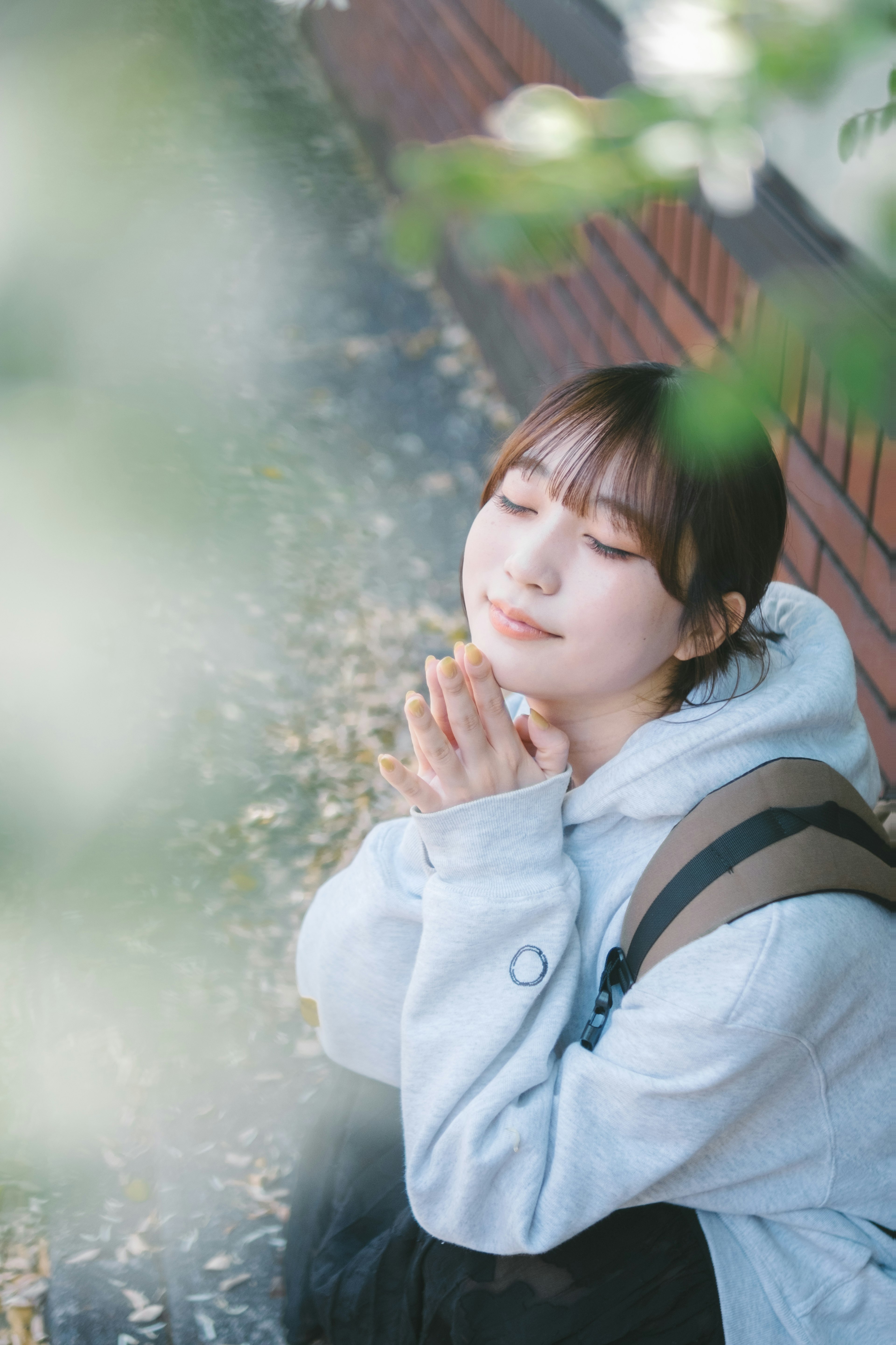 Young woman in a thoughtful pose under a tree